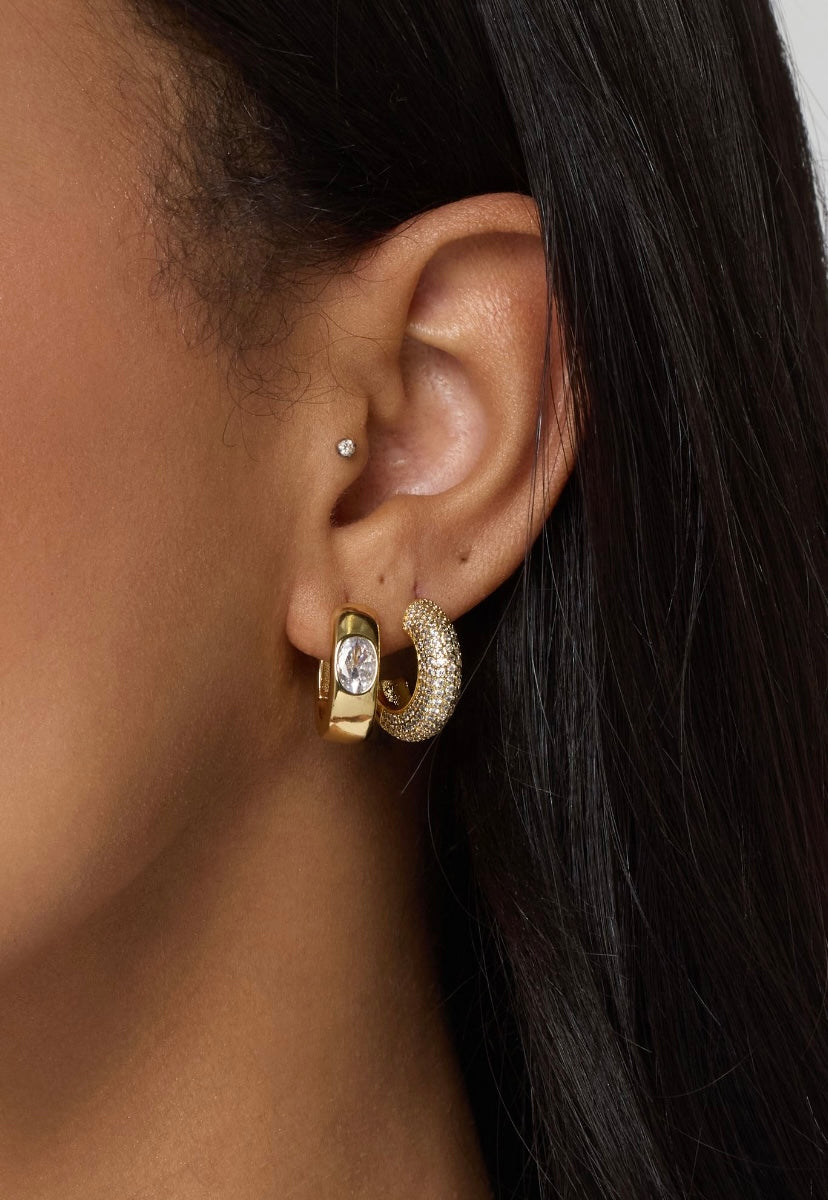 Close-up of a woman's ear wearing three Kinsey Designs gold filled earrings, including the Sax Hoop (.85" diameter), a small stud, and another hoop with a clear gem.