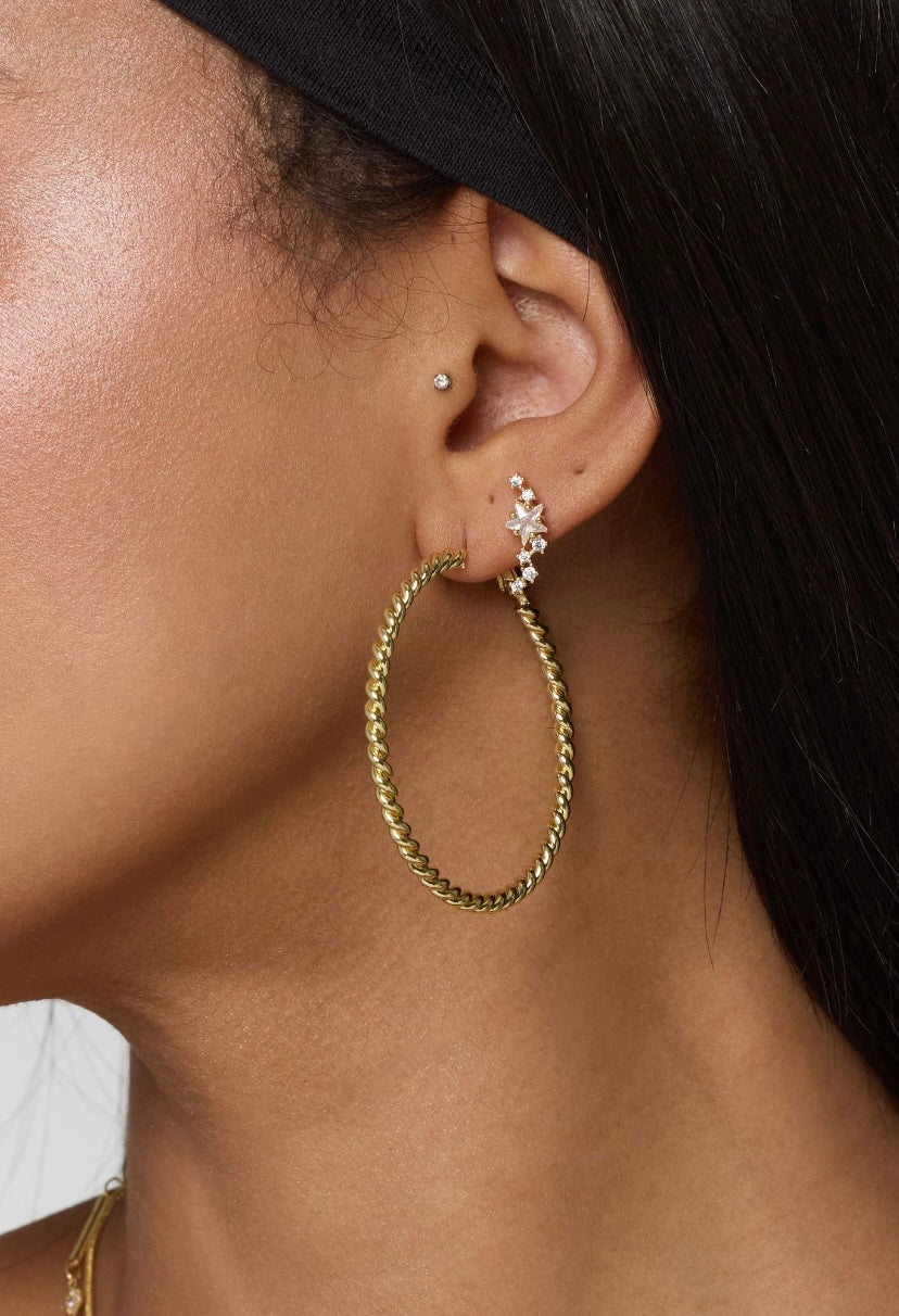 Close-up of a woman's ear wearing Kinsey Designs’ Starlette Climber, a gold filled hoop, a small stud, and a jeweled cubic zirconia ear cuff on the upper ear.