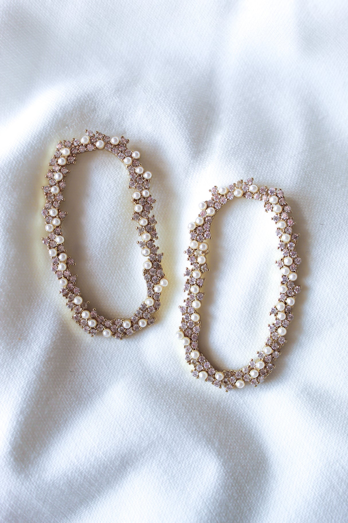Two oval-shaped, pearl and crystal hair clips on a white fabric backdrop—a chic accent that pairs effortlessly with Kinsey Designs’ Abbie Earring or your favorite sample sale jewelry.