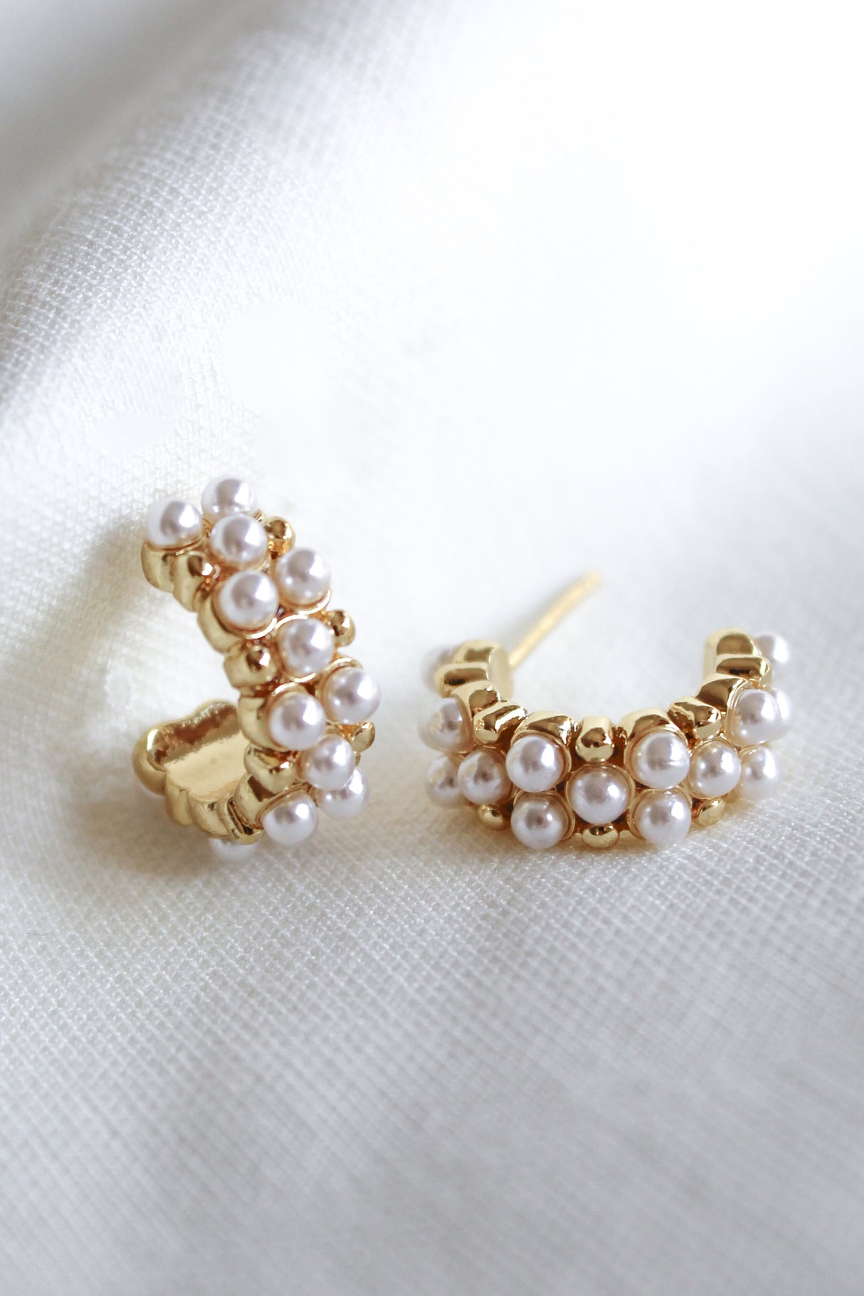 Aeroine Pearl Hoops by Kinsey Designs feature gold-filled hoops adorned with small white pearls, shown on a white textured fabric background.