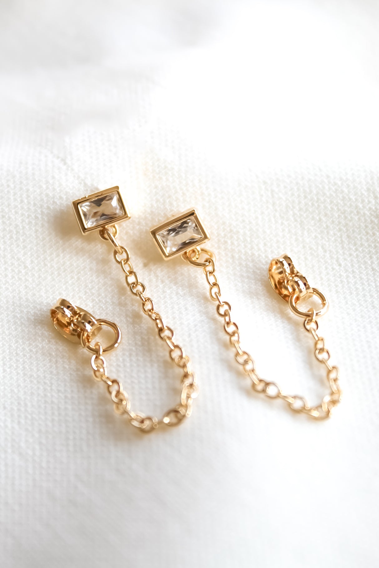 Astrid Earrings by Kinsey Designs Archives: gold filled with rectangular clear gemstones on a gold chain, displayed on white fabric. SAMPLE SALE—final sale.