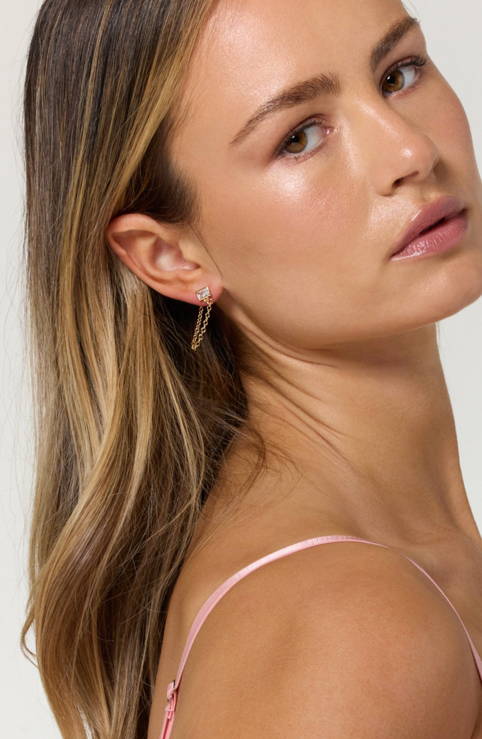 Woman with long blonde hair wears a pink strap top and gold filled Astrid Earrings by Kinsey Designs Archives, looking over her shoulder.