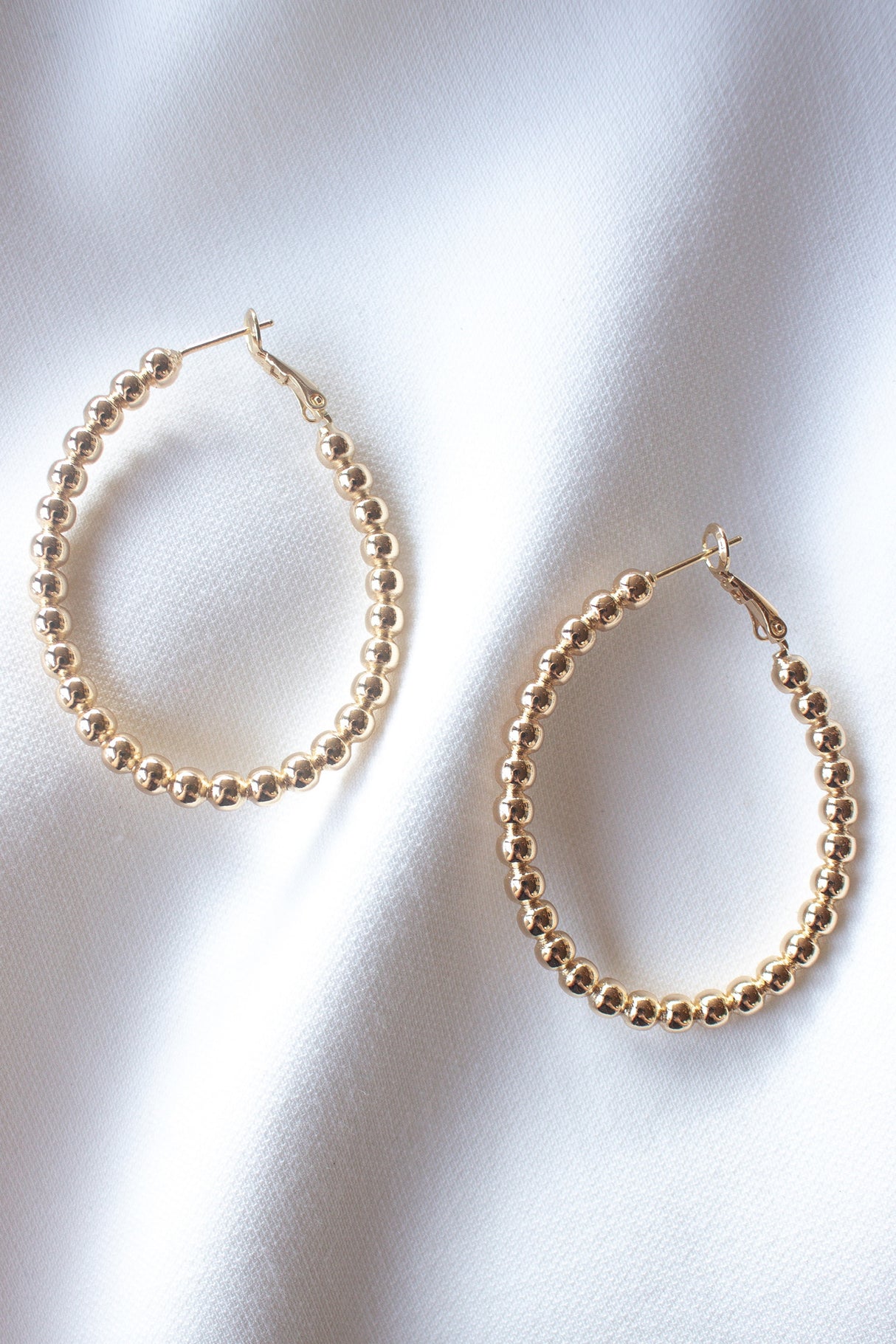 The Atlas Hoop by Kinsey Designs Archives—gold filled beaded hoop earrings—shown on white fabric. Elevate any look with this stunning sample sale find before it’s gone!.