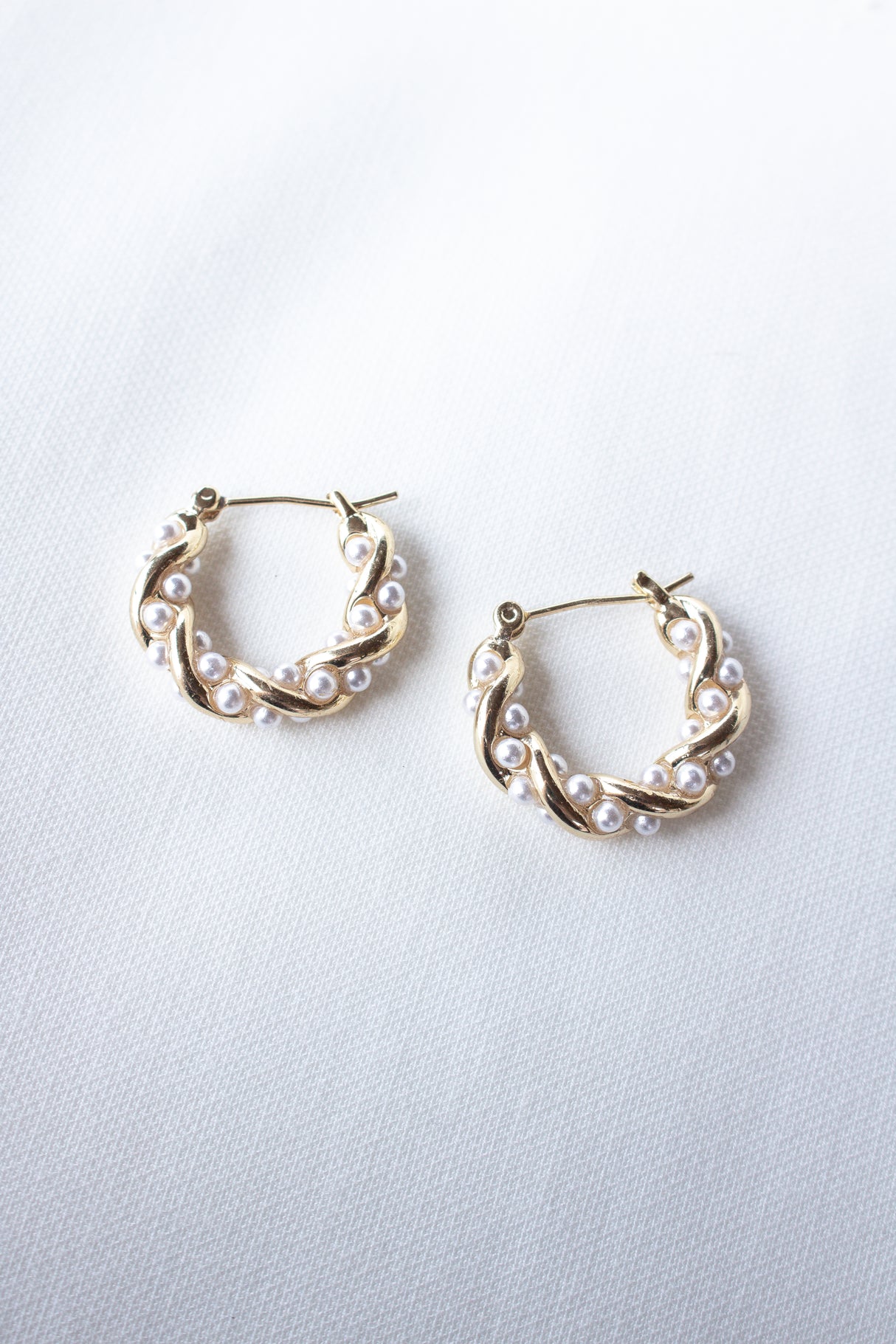 The Audrey Pearl Hoops by Kinsey Designs feature a twisted gold hoop adorned with small white pearls, adding timeless elegance and making them the perfect pearl hoop earrings for any occasion.