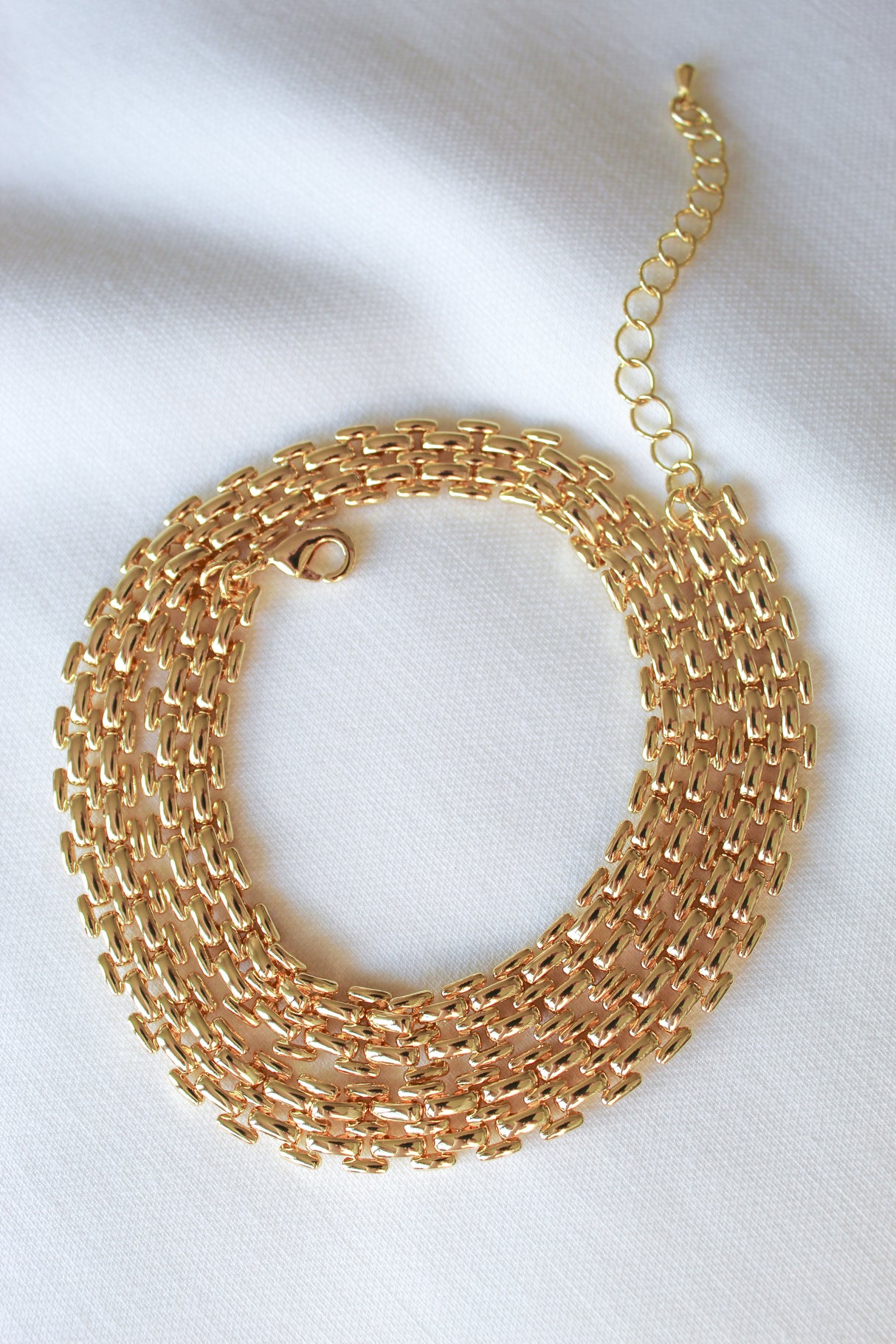 The Basque Necklace by Kinsey Designs Archives features a chunky chain and adjustable clasp, displayed coiled in a circle on a white fabric background.
