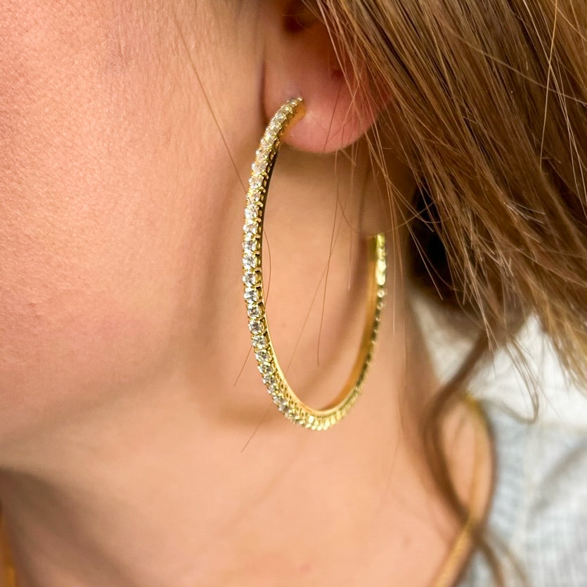 Close-up of a woman's ear wearing the Blaze Hoop by Kinsey Designs Archives, a large gold filled earring encrusted with sparkling cubic zirconia stones.
