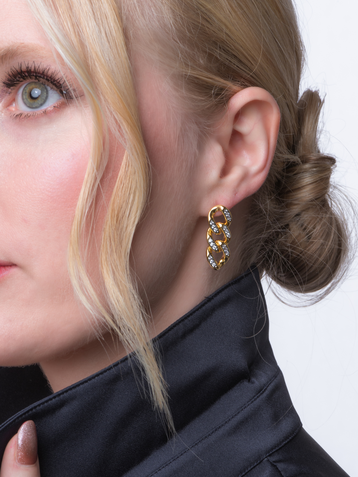 Close-up of a woman with blonde hair wearing the Kinsey Designs Boden Chain Earring, chic gold chain link earrings with silver accents, paired with a dark jacket.