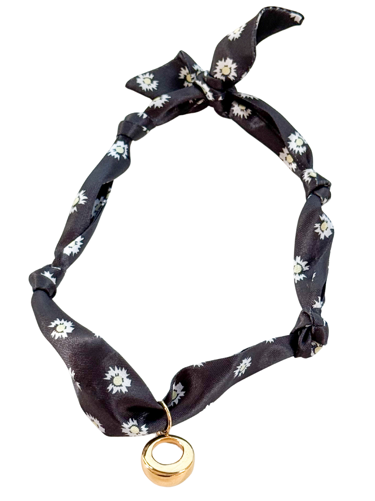 The Cuneo Scarf Necklace by Kinsey Designs features black floral fabric, a gold vintage-inspired circular pendant, tied ends, and an adjustable design, displayed on a white background.