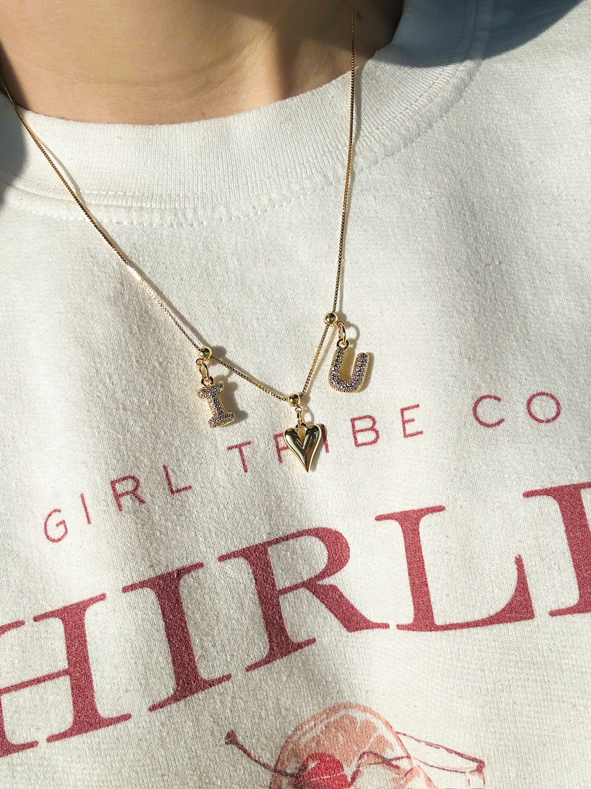 Kinsey Designs Collection’s Bubble Letter Grip Charm Letter A adds style to a white sweatshirt with red text.
