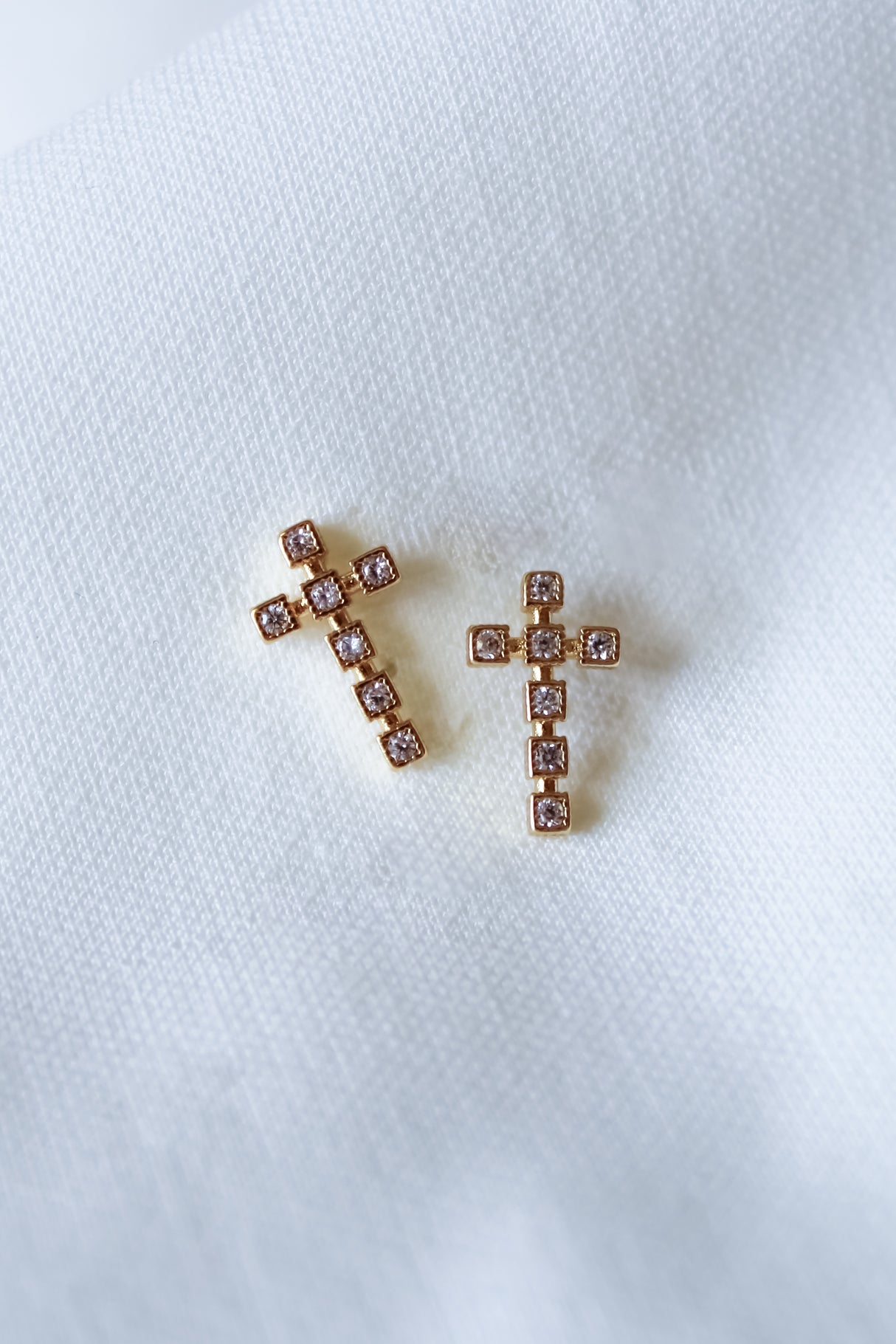 The Easton Stud by Kinsey Designs features gold-filled, cross-shaped earrings with small crystals, beautifully displayed on white fabric. Shop this elegant pair now during our exclusive sample and final sale—don’t miss out!.