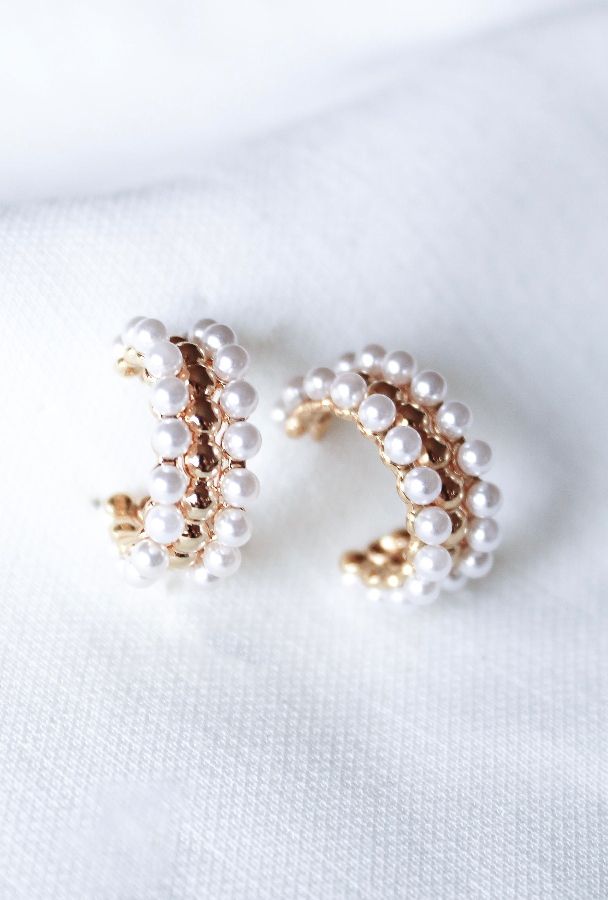 Elsie Hoop by Kinsey Designs Archives: gold hoop earrings with small white pearls, elegantly shown on a white textured fabric.