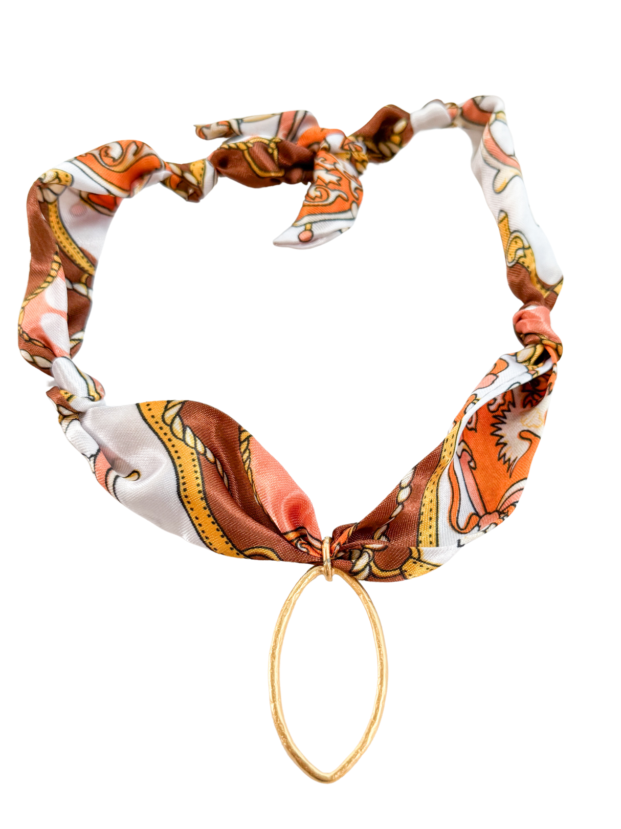 The Forli Scarf Necklace by Kinsey Designs features a colorful patterned adjustable scarf with a gold oval pendant, knotted at the top for a stylish twist on the classic vintage pendant scarf.