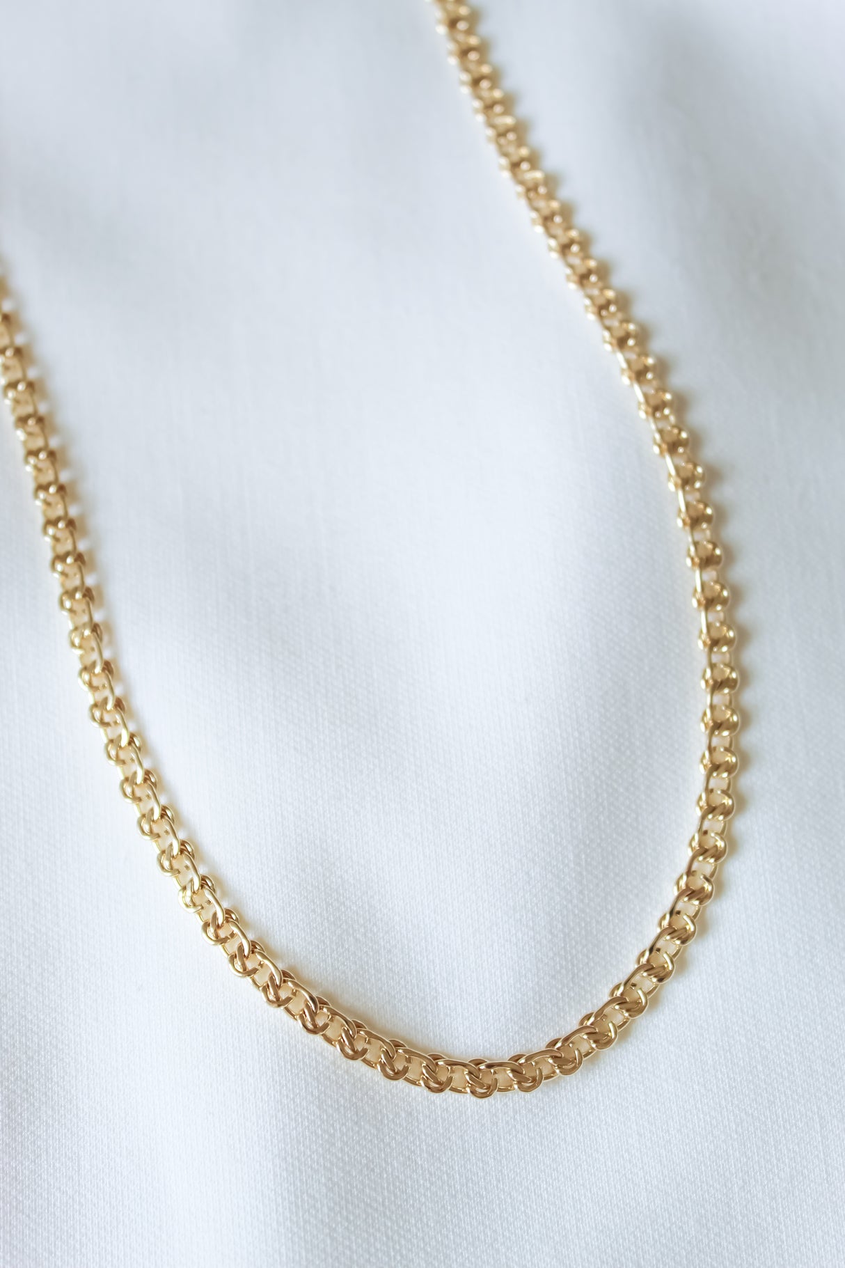 The Gabi Necklace by Kinsey Designs Archives, an 18-inch gold filled piece, is showcased on a white fabric background—don’t miss this exclusive sample sale!.