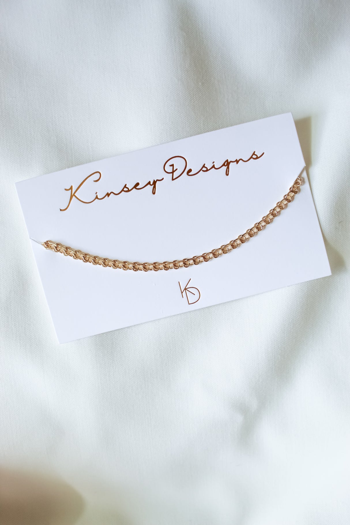 A Gabi Necklace by Kinsey Designs Archives, displayed on a brand card against white fabric—perfect for pairing with your favorite gold-filled jewelry.