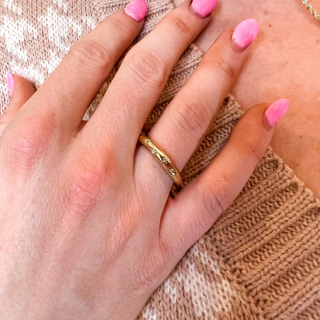 A hand with pink polished nails wears the Gia Ring by Kinsey Designs Archives, gold-plated in size 7, resting on a beige knit sweater.