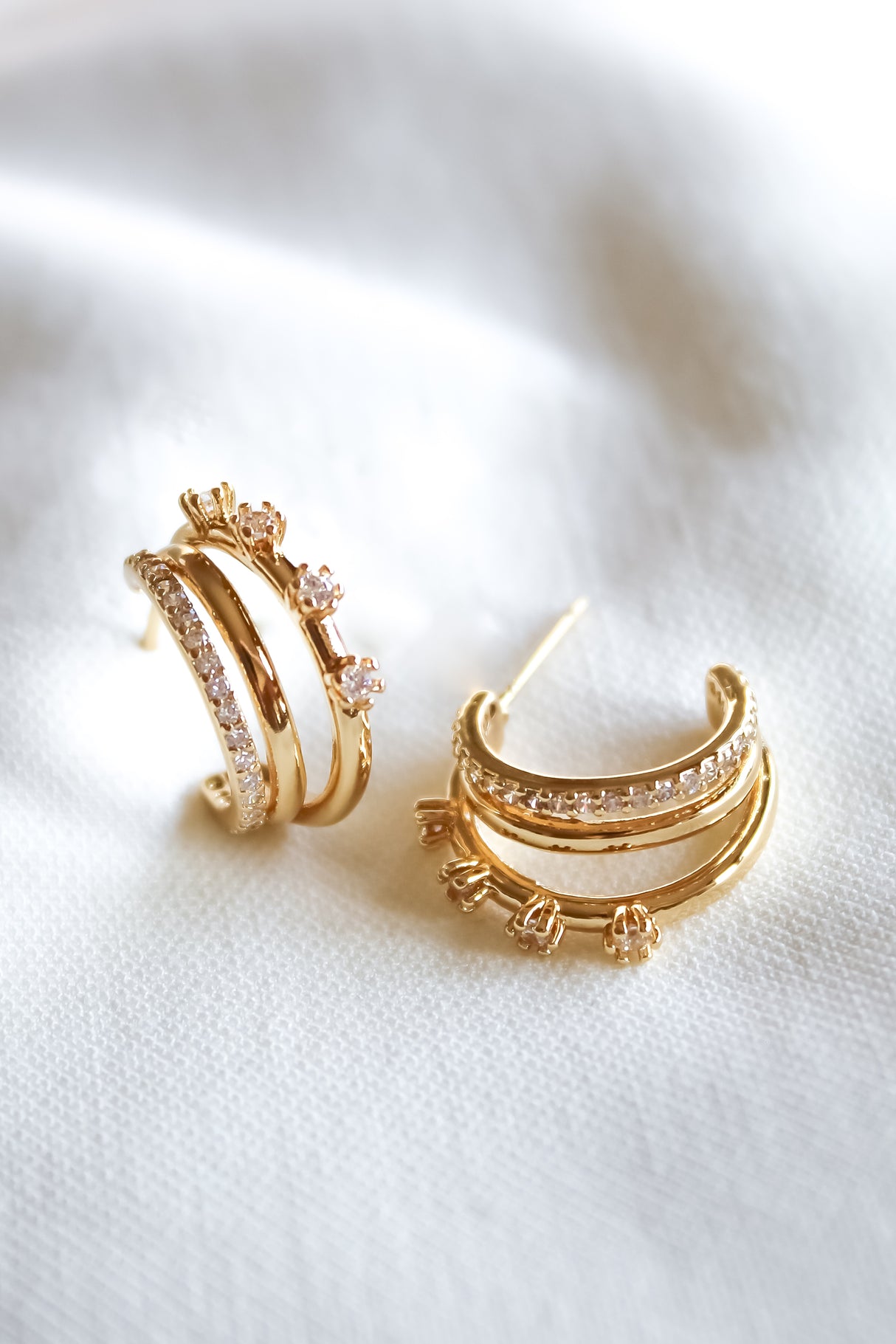 The Hallie Earrings by Kinsey Designs are gold-filled hoops, .75" in diameter, featuring sparkling stones and floral accents—ideal for elevating your jewelry collection. Displayed on a white fabric background.