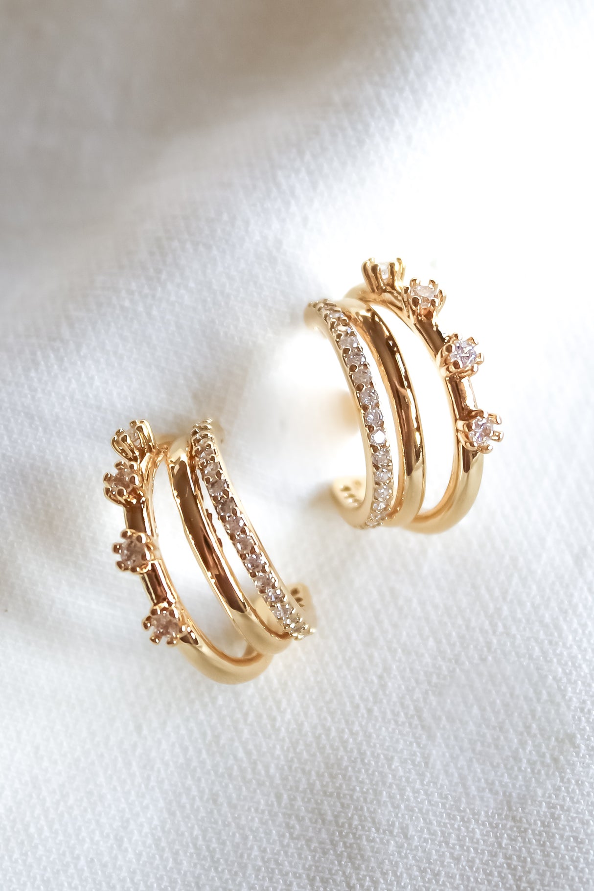 The Hallie Earring by Kinsey Designs features multiple gold filled hoops with small embedded crystals (.75" diameter), shown on a white fabric background—a delicate accessory perfect for any occasion.