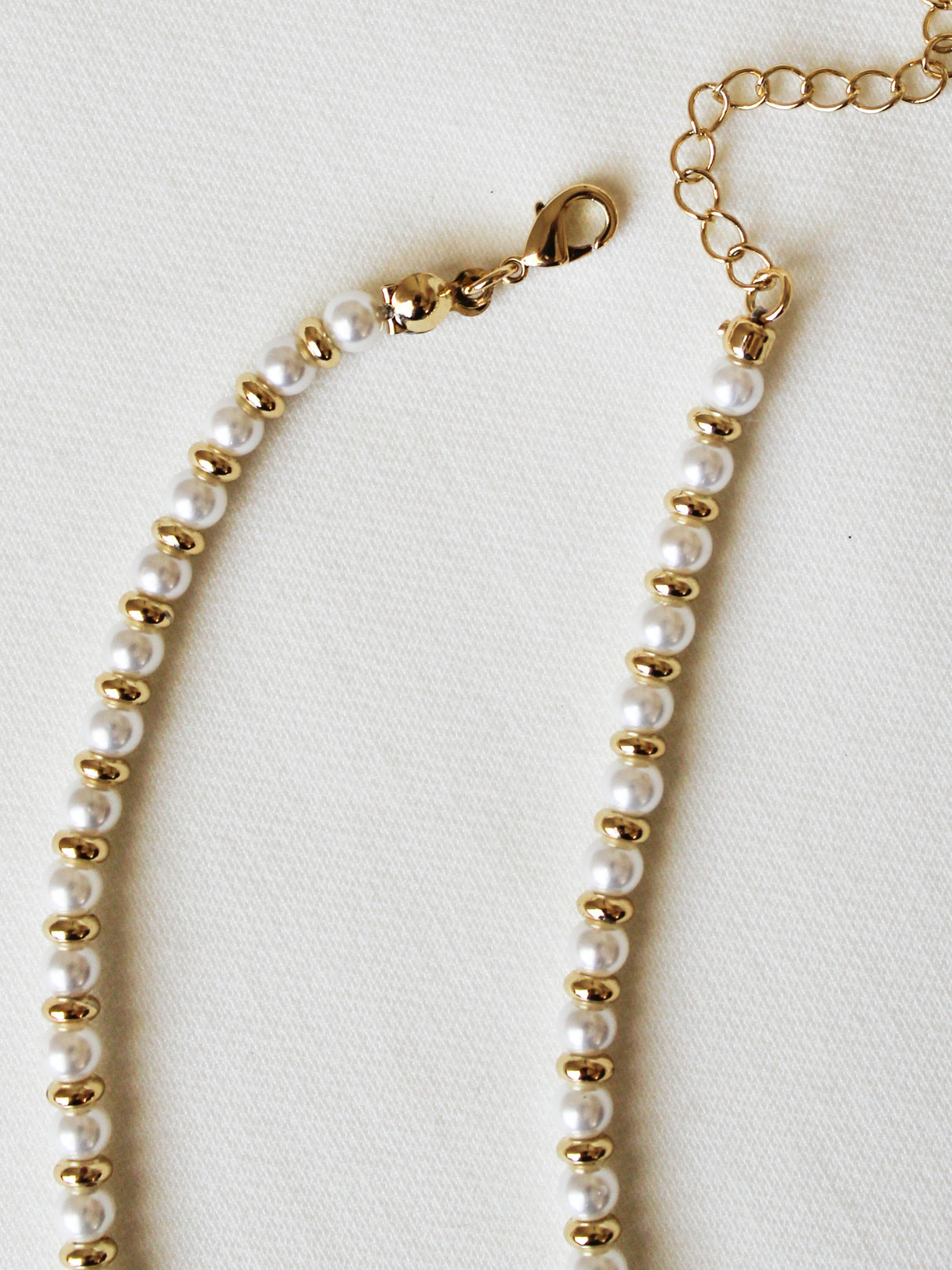 The Haven Necklace by Kinsey Designs is a pearl beaded necklace featuring gold-filled accents, a lobster clasp, and an adjustable chain, shown on a light fabric background.