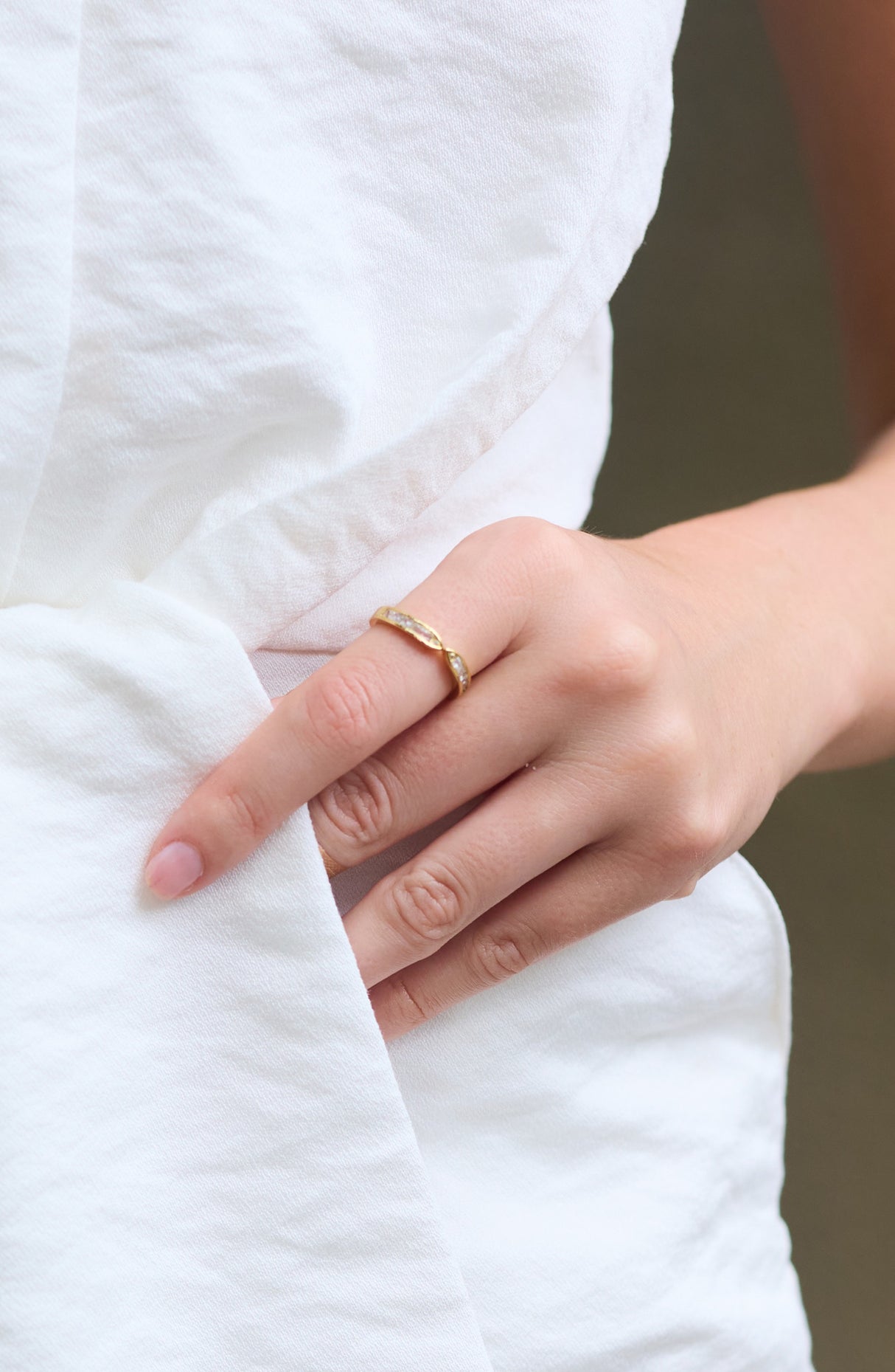 A hand wearing the Hayden Ring by Kinsey Designs rests on white textured fabric.