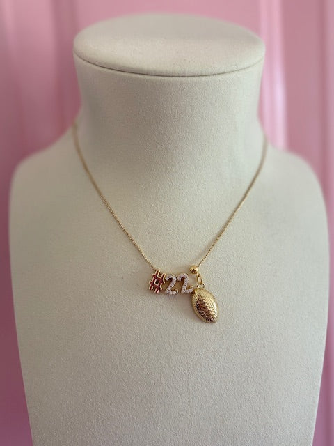 The Kinsey Designs Lux Numerical Slide Charm necklace features gold "2023" number charms and a petite gold football pendant—ideal for personalized jewelry lovers and elegantly displayed on a bust.