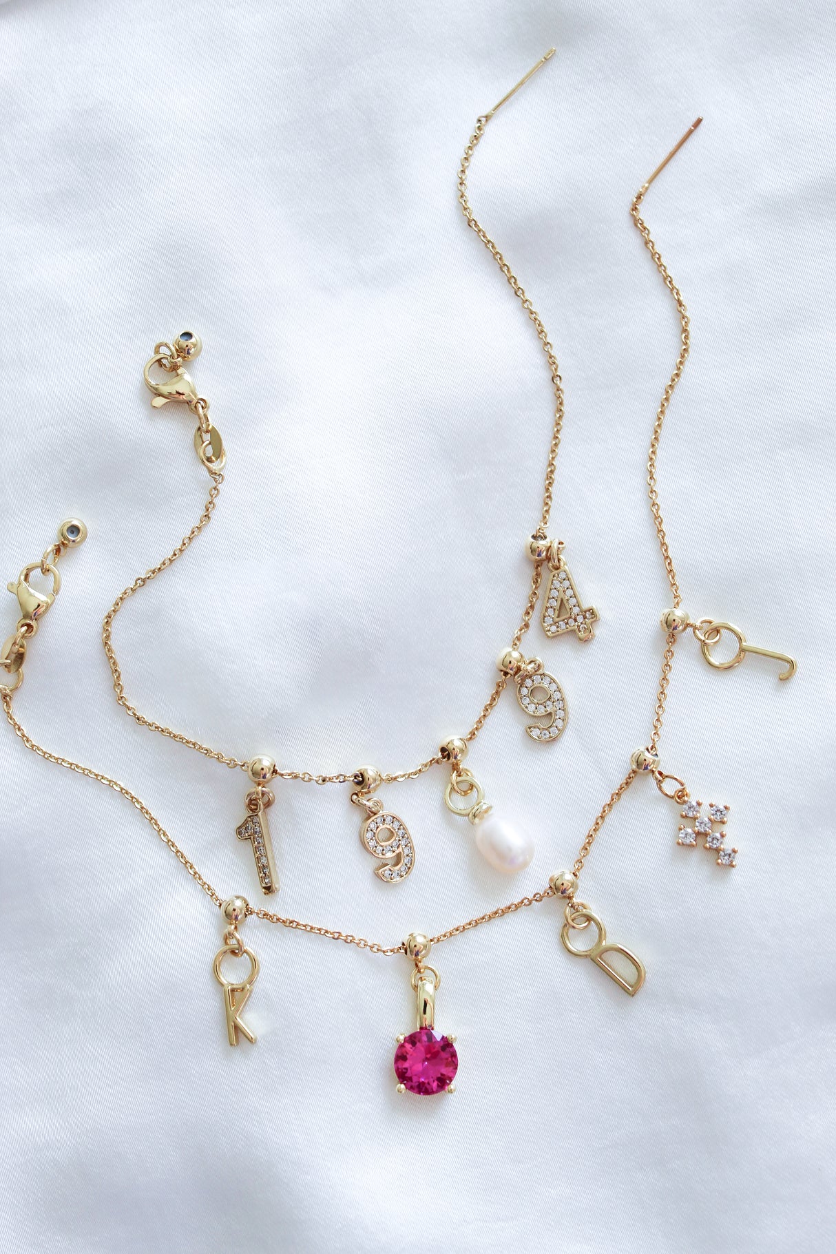 Three gold necklaces with Kinsey Designs Archives Letter Grip Charms and jeweled accents displayed on white fabric—ideal for personalized jewelry lovers seeking a unique, gold-filled charm.