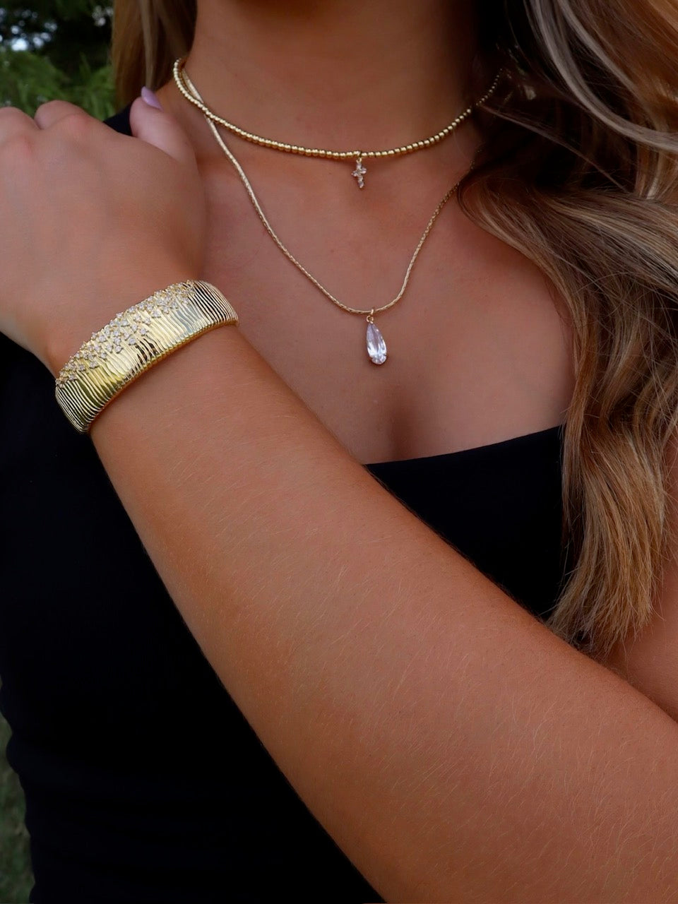 A woman wearing the Kinsey Designs Charlotte Drop Necklace, featuring a teardrop cubic zirconia pendant, paired with a matching bracelet.