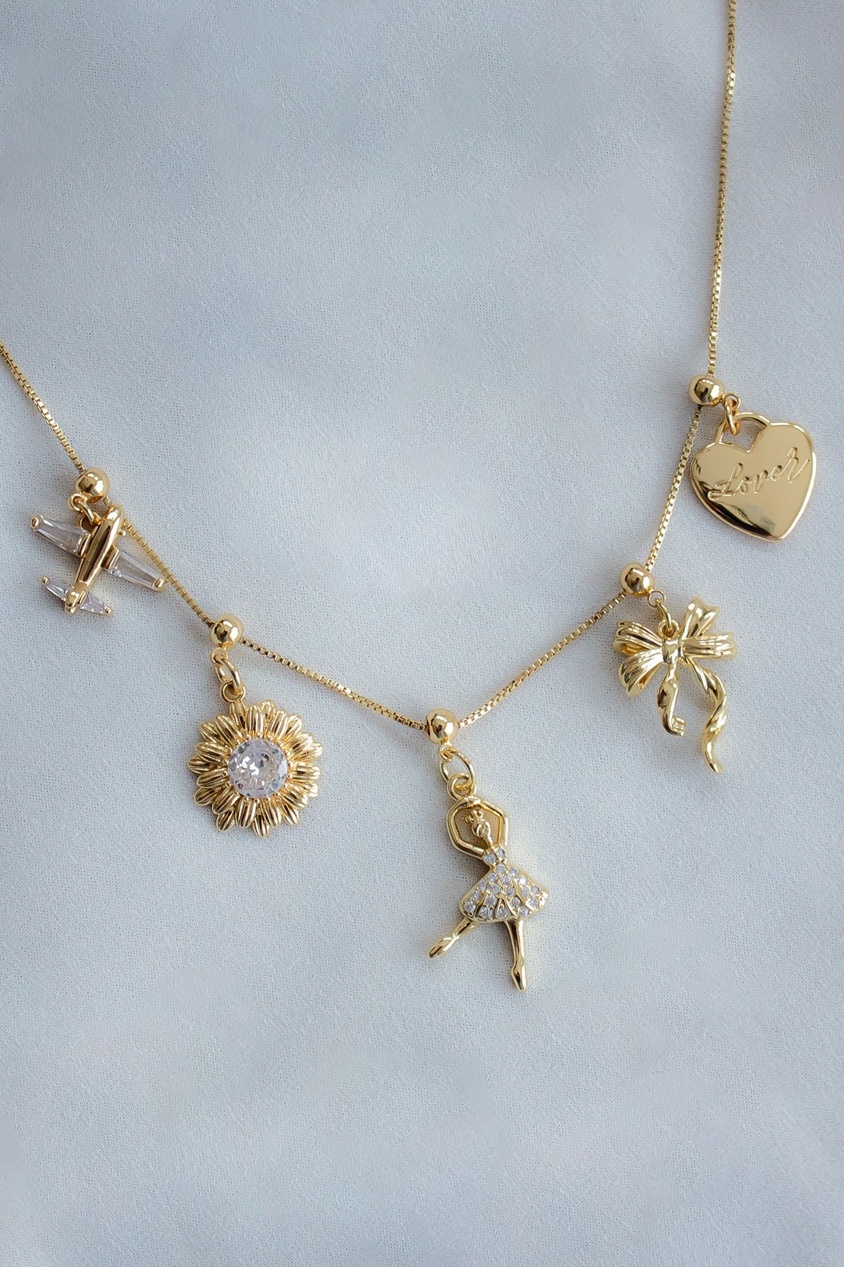 The Kinsey Designs Dancer Grip Charm necklace features airplane, sunflower, ballerina, bow, and heart "love" charms—an ideal gift for dance enthusiasts.