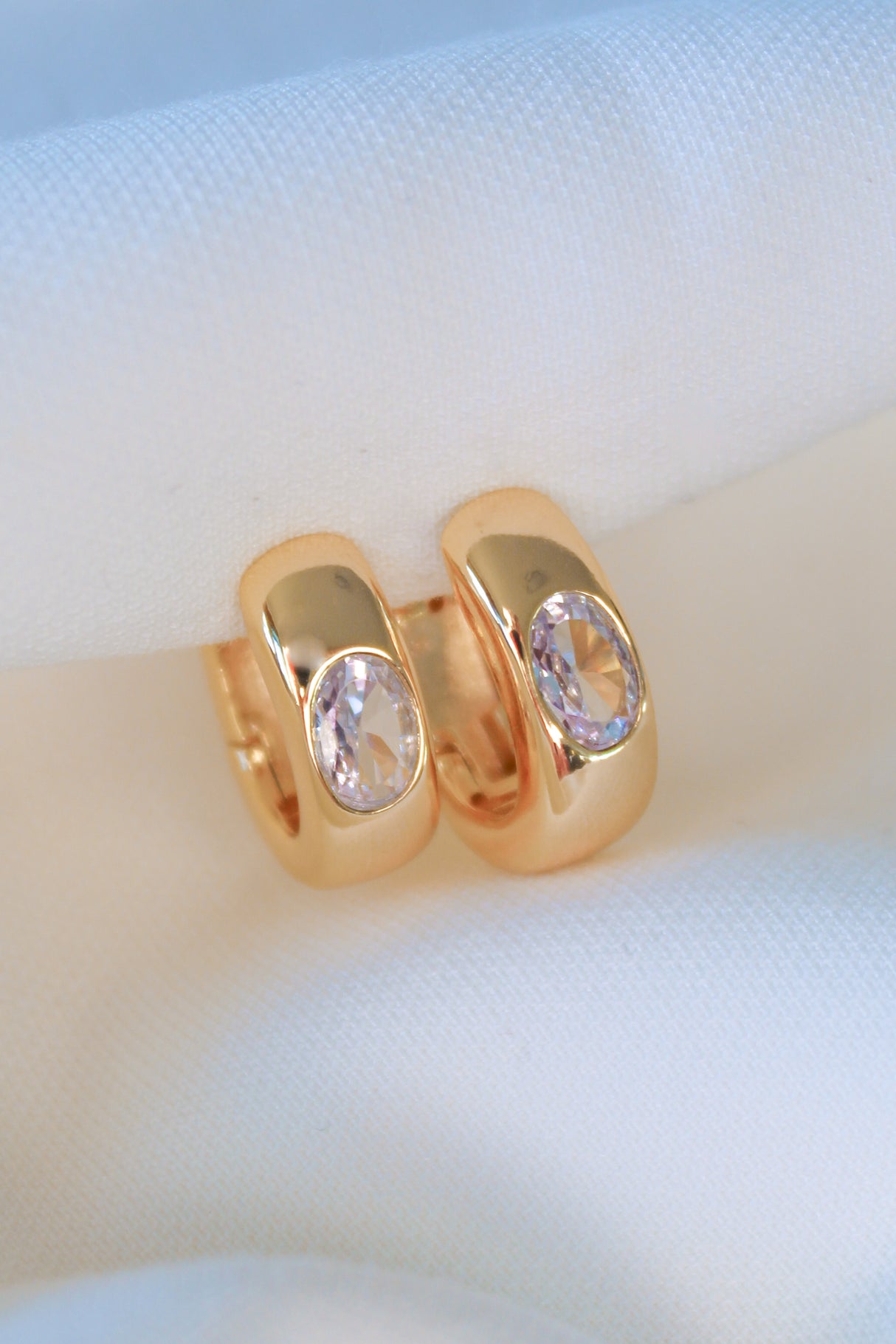 The Jack Huggie by Kinsey Designs, gold filled hoop earrings with oval gemstones, displayed on soft white fabric—ideal for those seeking unique sample sale jewelry.