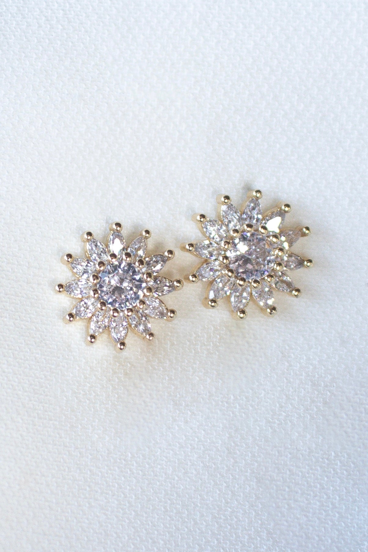The Lana Stud by Kinsey Designs Archives features gold filled floral studs with sparkling CZ accents, displayed on a soft white fabric background.
