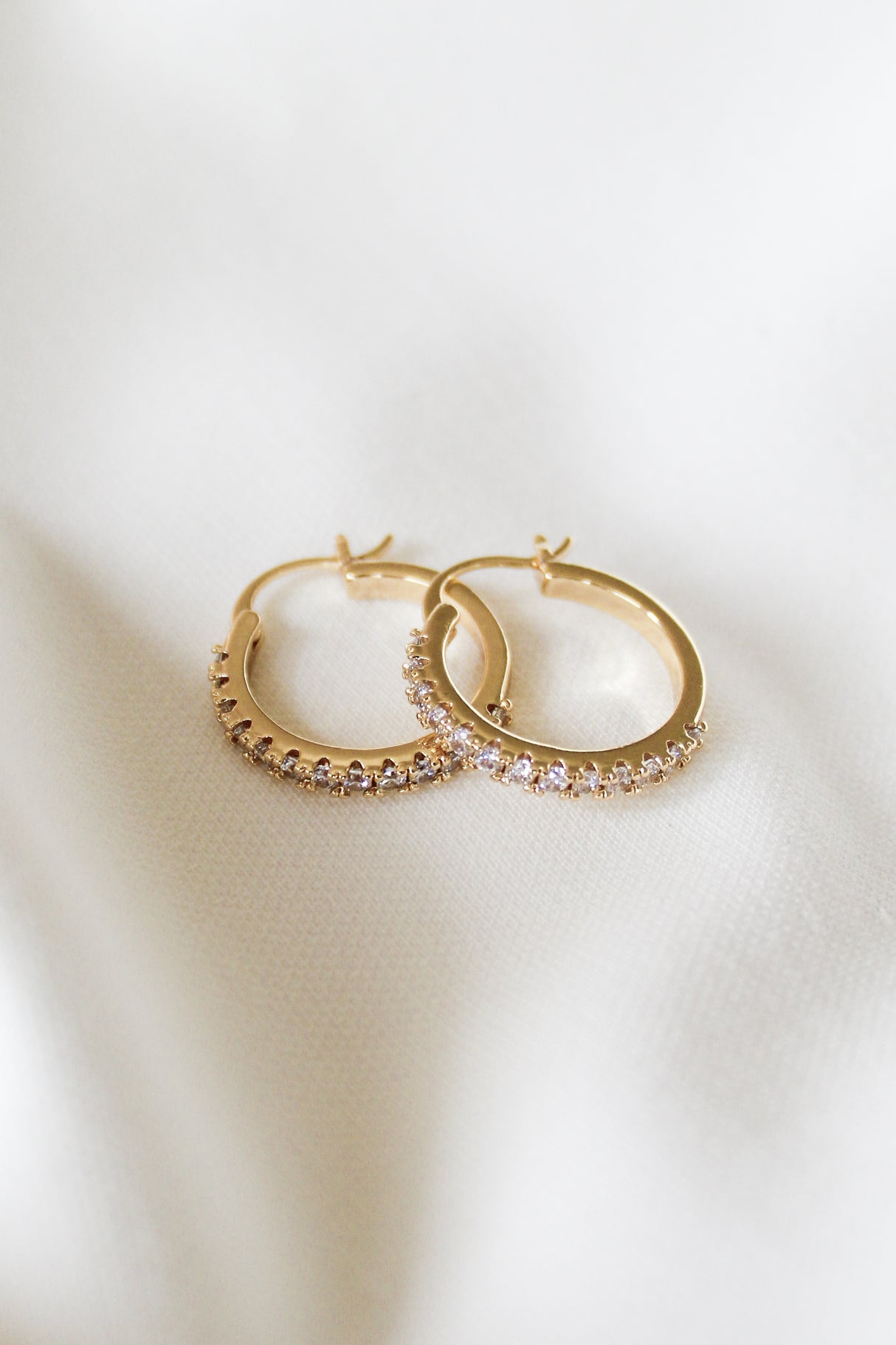 The Lane Hoop by Kinsey Designs features small sparkling stones on gold filled hoops, each measuring .75" in circumference, displayed on a soft white fabric background.