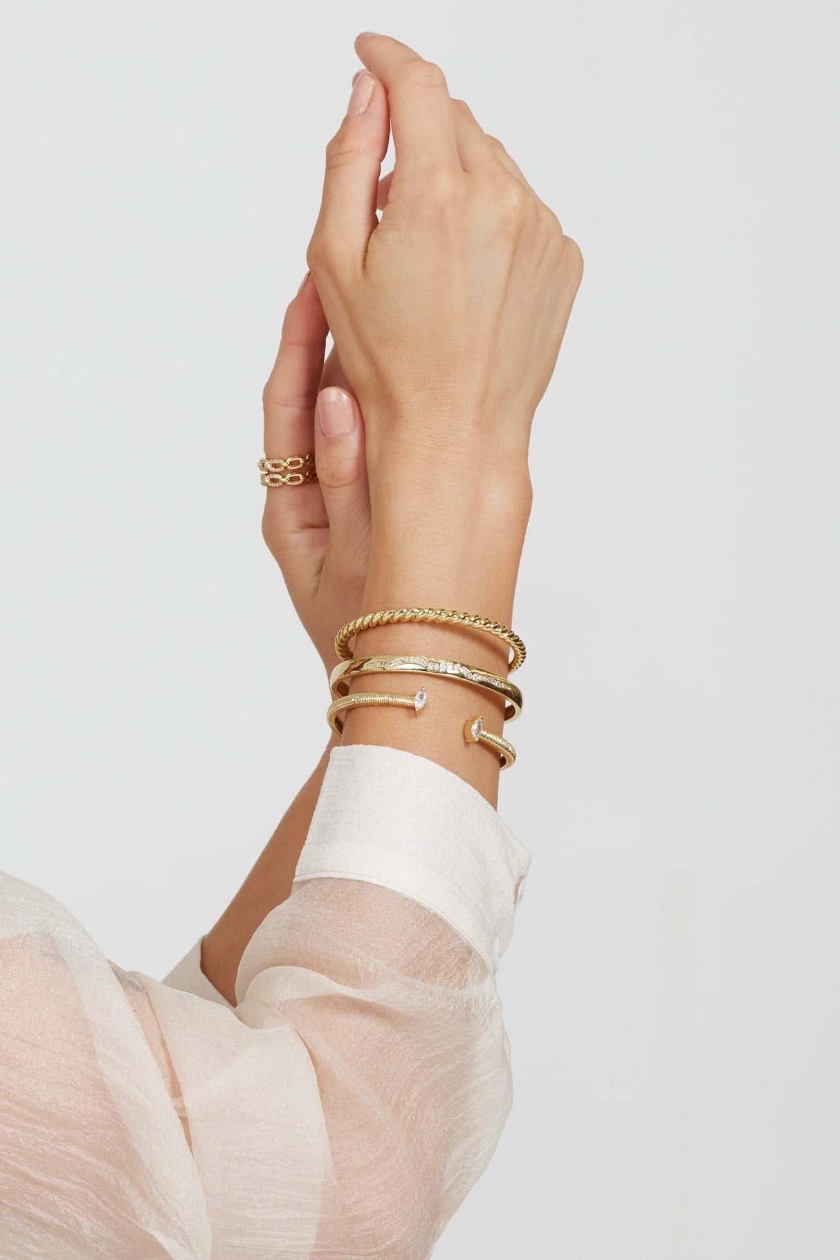 A hand wearing the Kinsey Designs Archives Lily Cuff bracelet and a ring, shot against a white background with a sheer white sleeve visible.