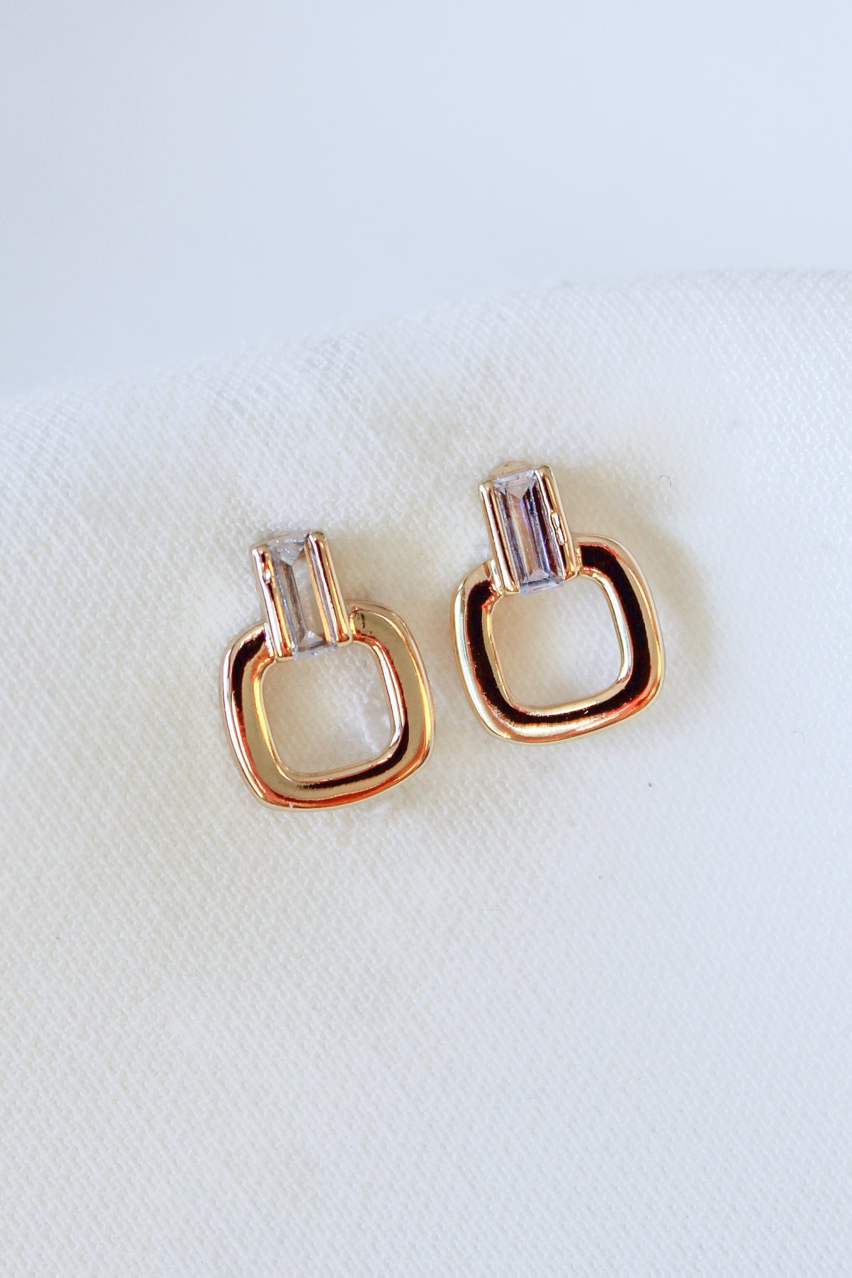 Kinsey Designs Lucky Post earrings feature gold-filled and crystal studs in geometric shapes, each measuring 0.5" long, shown on a white fabric background.