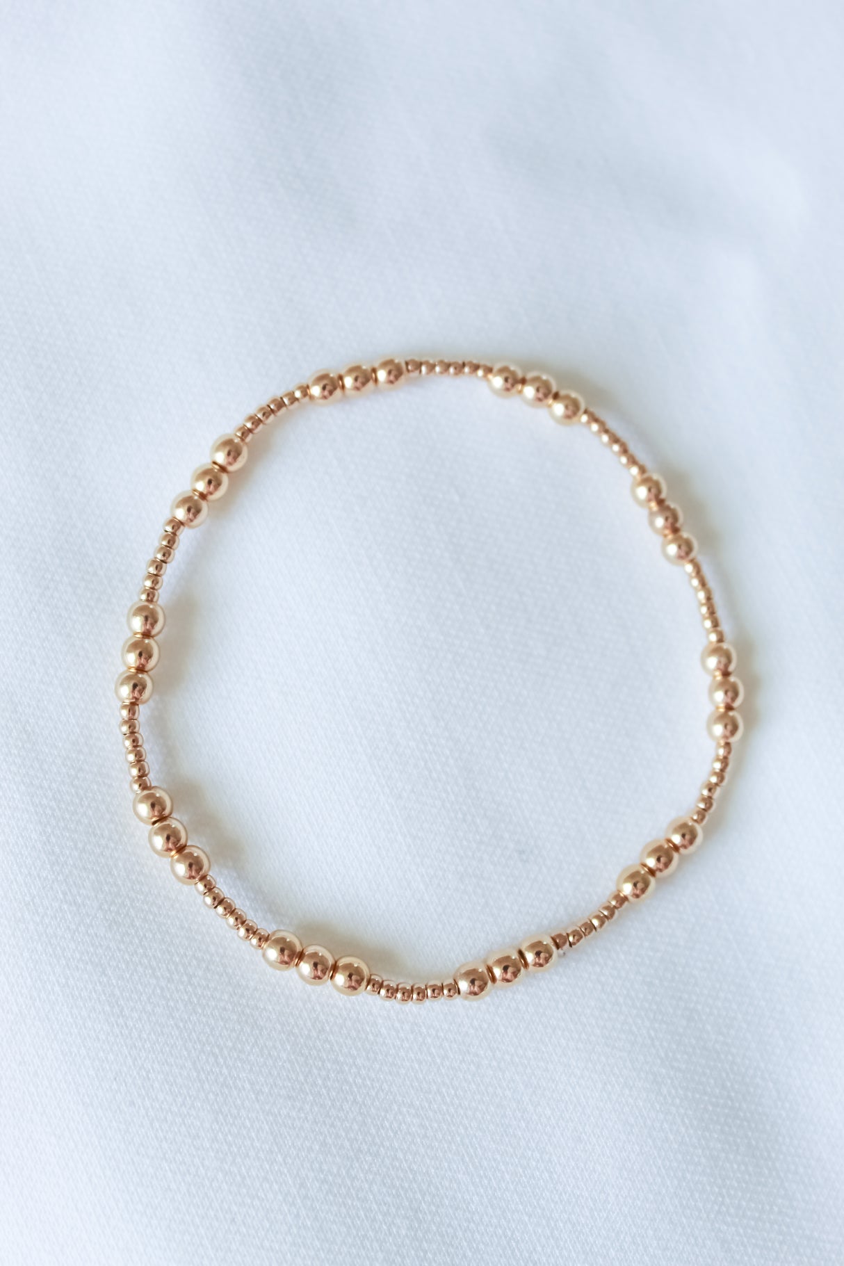 The Mia Bracelet by Kinsey Designs features a delicate gold-filled beaded, adjustable stretch design and is shown on a white fabric background. Available in multiple sizes—an ideal sample sale find.