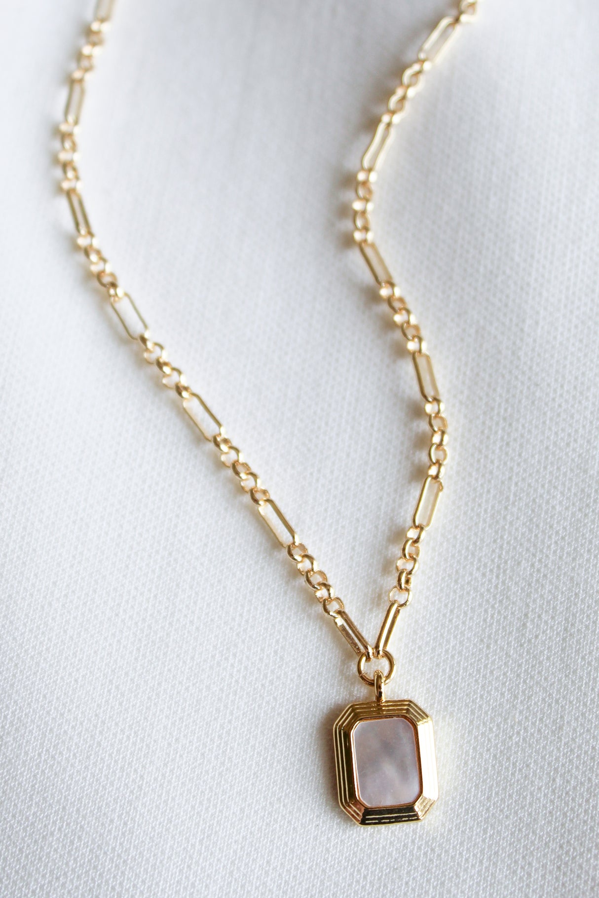 The Mirabelle Pendant Necklace by Kinsey Designs Archives features a gold-filled 20" chain with a rectangular mother-of-pearl pendant, showcased on white fabric—a perfect pick from our sample sale.