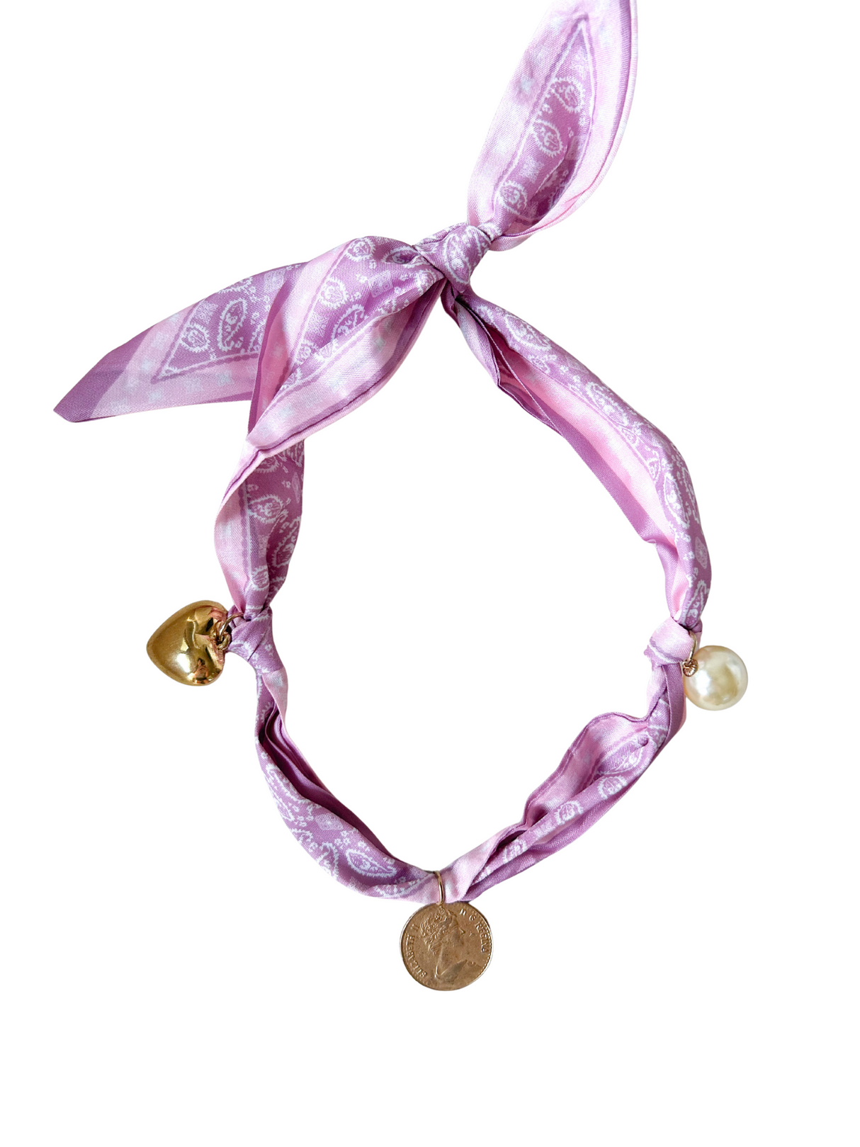 The Portofino Scarf Necklace by Kinsey Designs features a pink paisley print with gold heart, coin, and pearl charms in a loose knot. This adjustable accessory brings charming vintage style to any outfit.