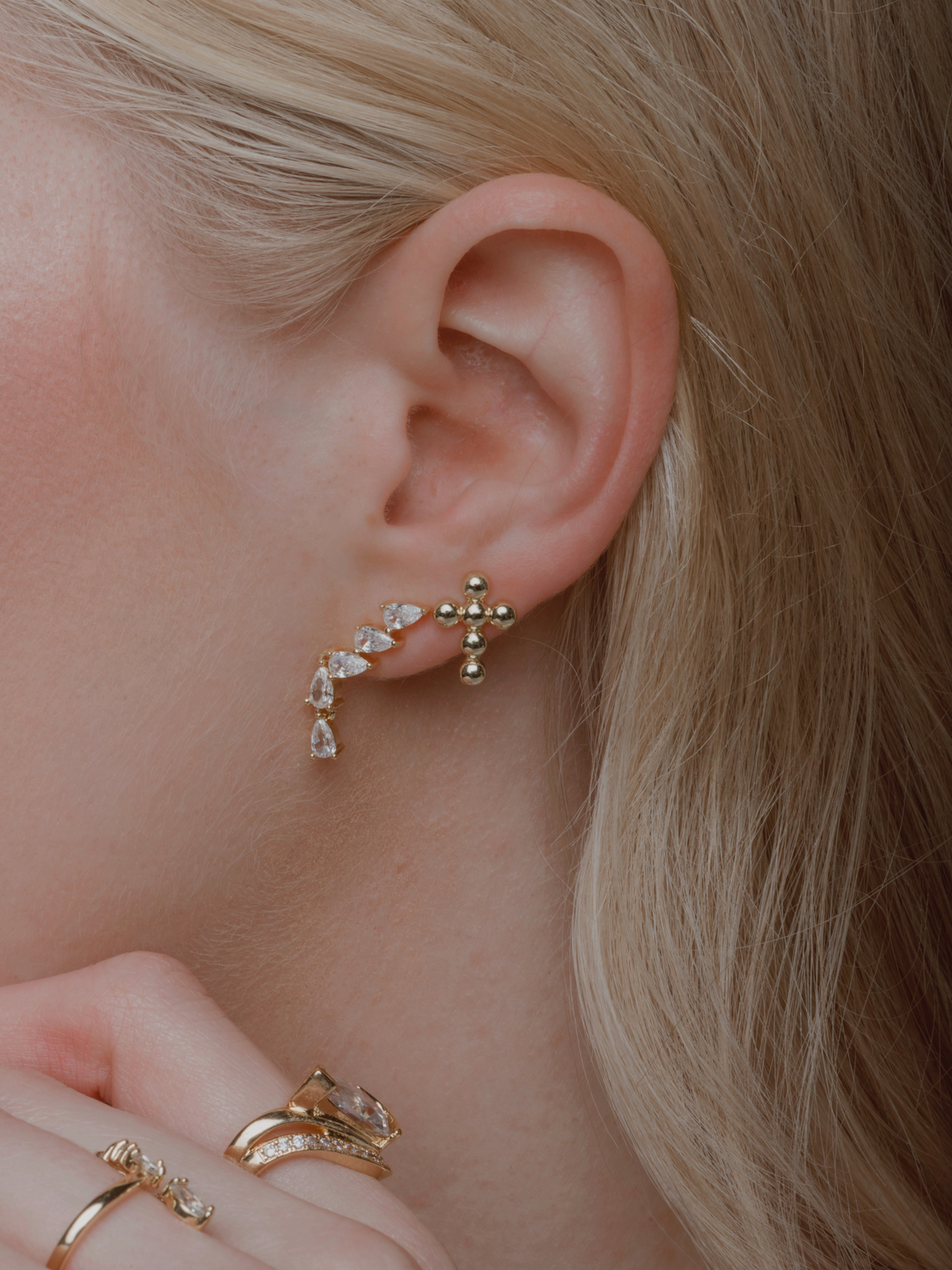 Close-up of a woman's ear wearing the Kinsey Designs Paloma Teardrop Climber Earring and rings, showcasing the intricate details of her jewelry.