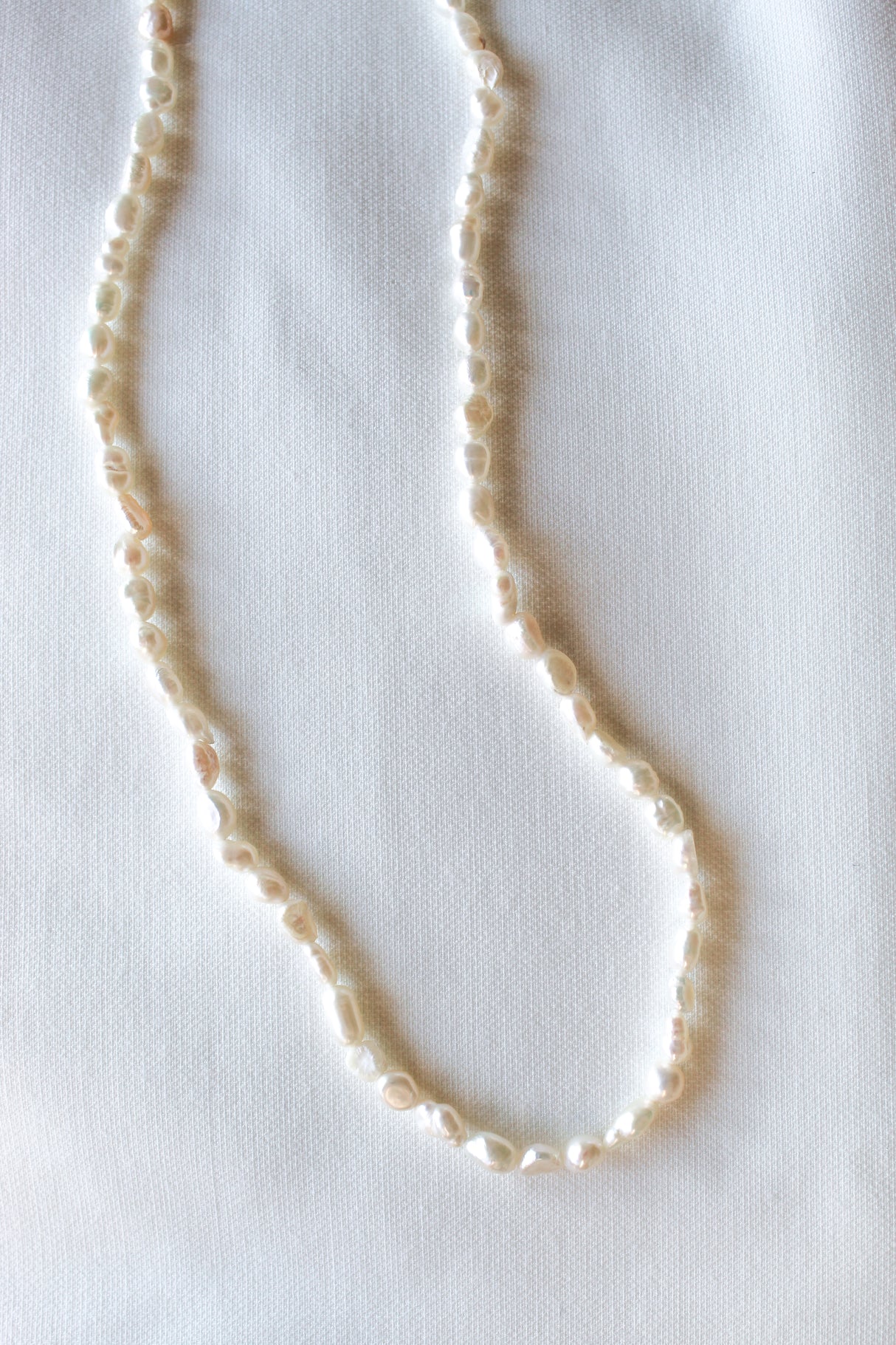 The Kinsey Designs Pearl Layering Necklace is displayed on textured white fabric, highlighting the elegance and craftsmanship of this artisanal pearl jewelry.