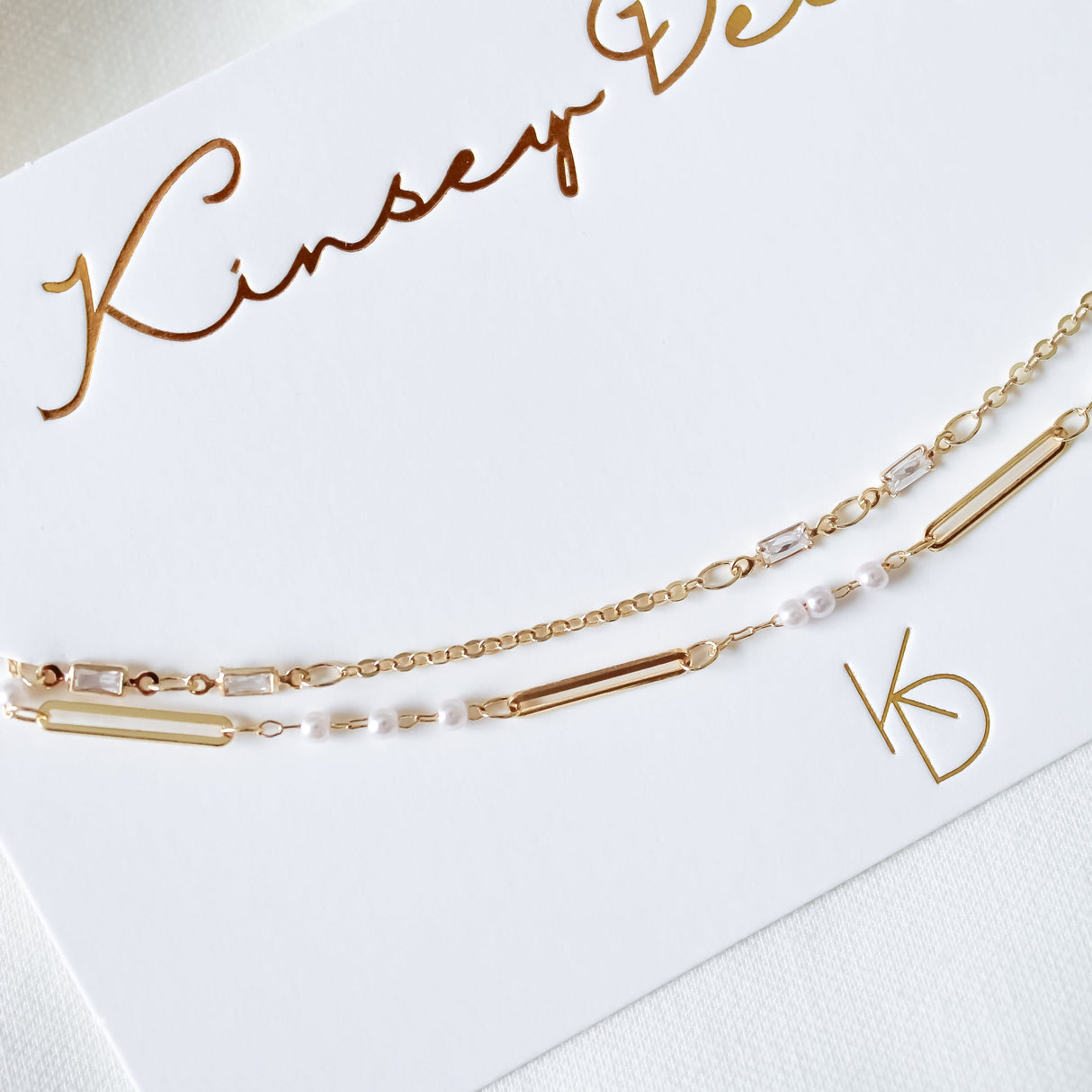The Pelly Layer Necklace by Kinsey Designs features a delicate gold chain with rectangular and small white beads—perfect for layering with your favorite pieces.