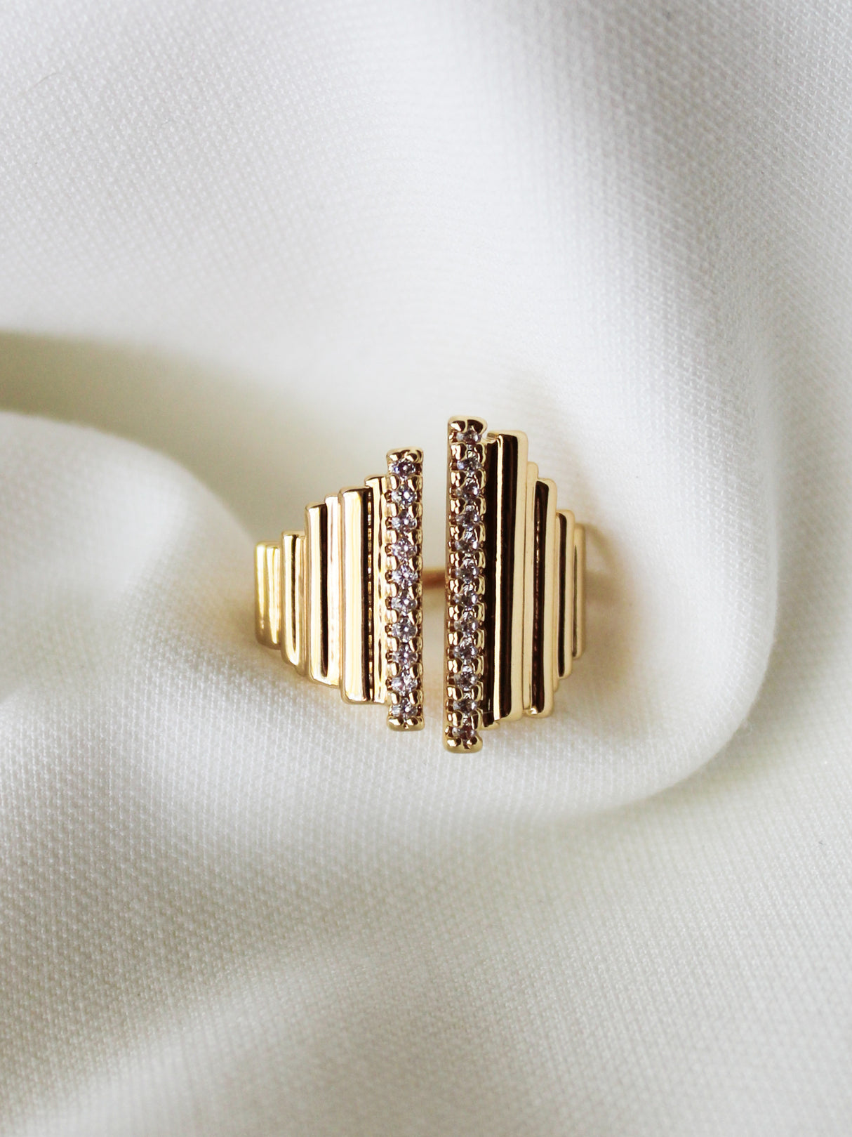 The Kinsey Designs Petra Ring features a vertical bar design with small gemstones, shown on white textured fabric—a stunning statement piece for any occasion.
