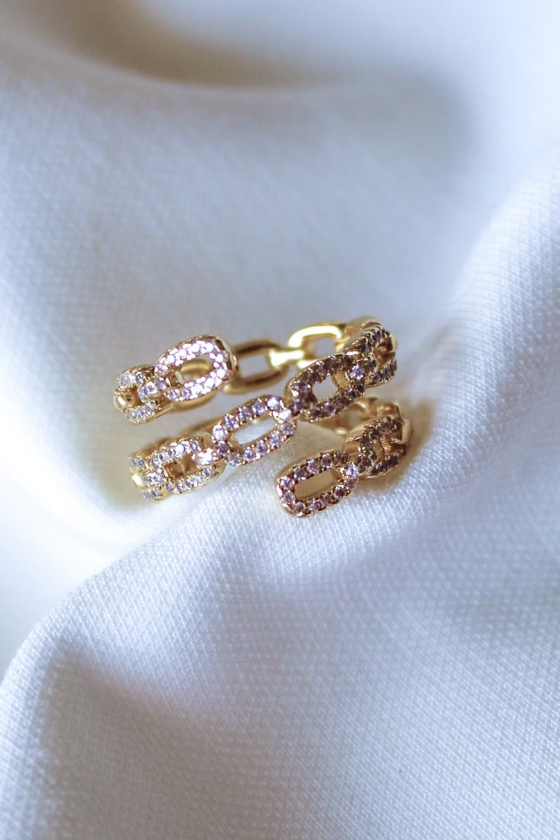 The Peyton Lux Ring by Kinsey Designs Archives, featuring chunky oval links and pink gemstones, rests on soft white fabric, highlighting its elegant yet modern style.