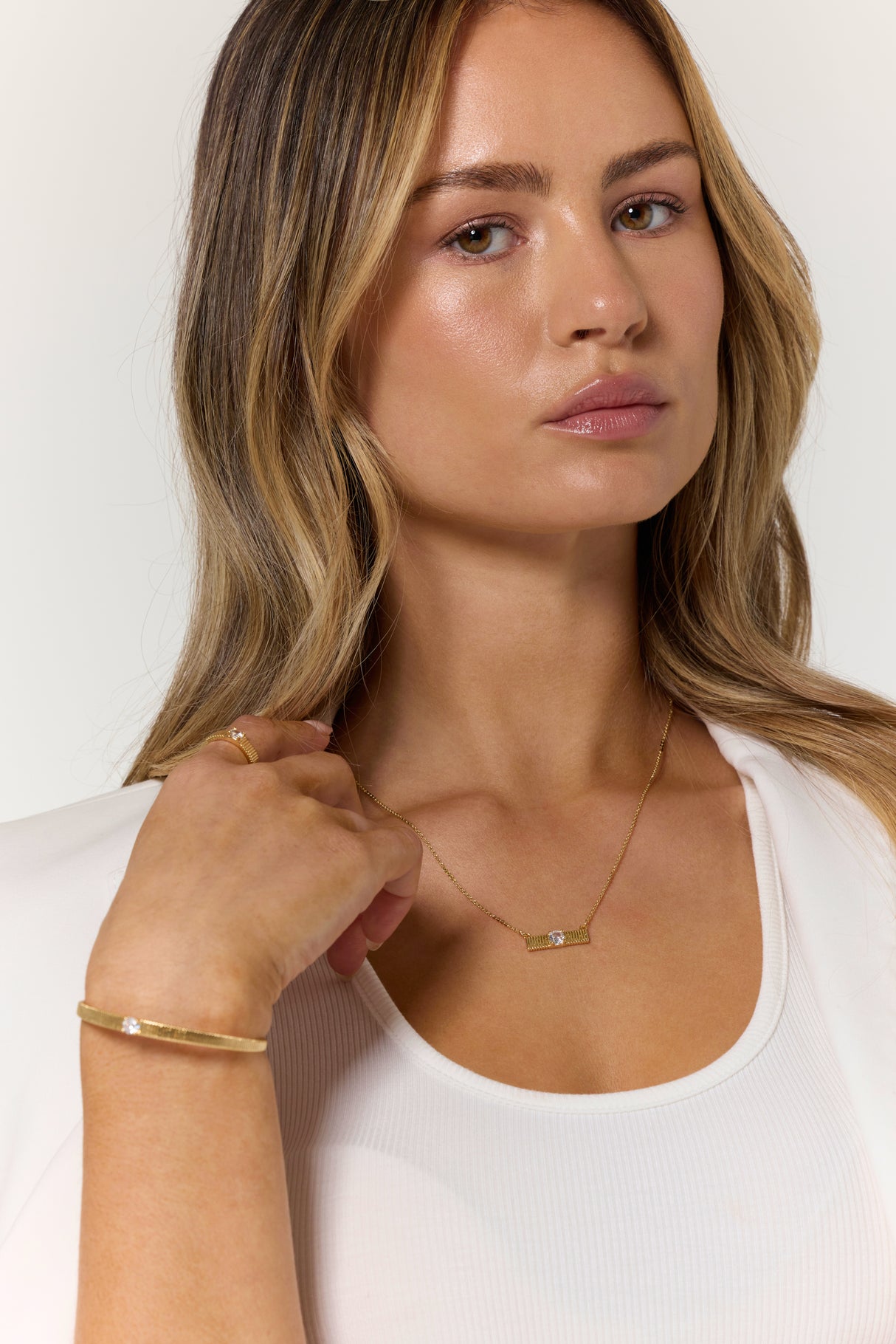 Woman with long blonde hair wears the Kinsey Designs Quinn Cuff gold filled jewelry, paired with a white top and white blazer, as she looks at the camera.