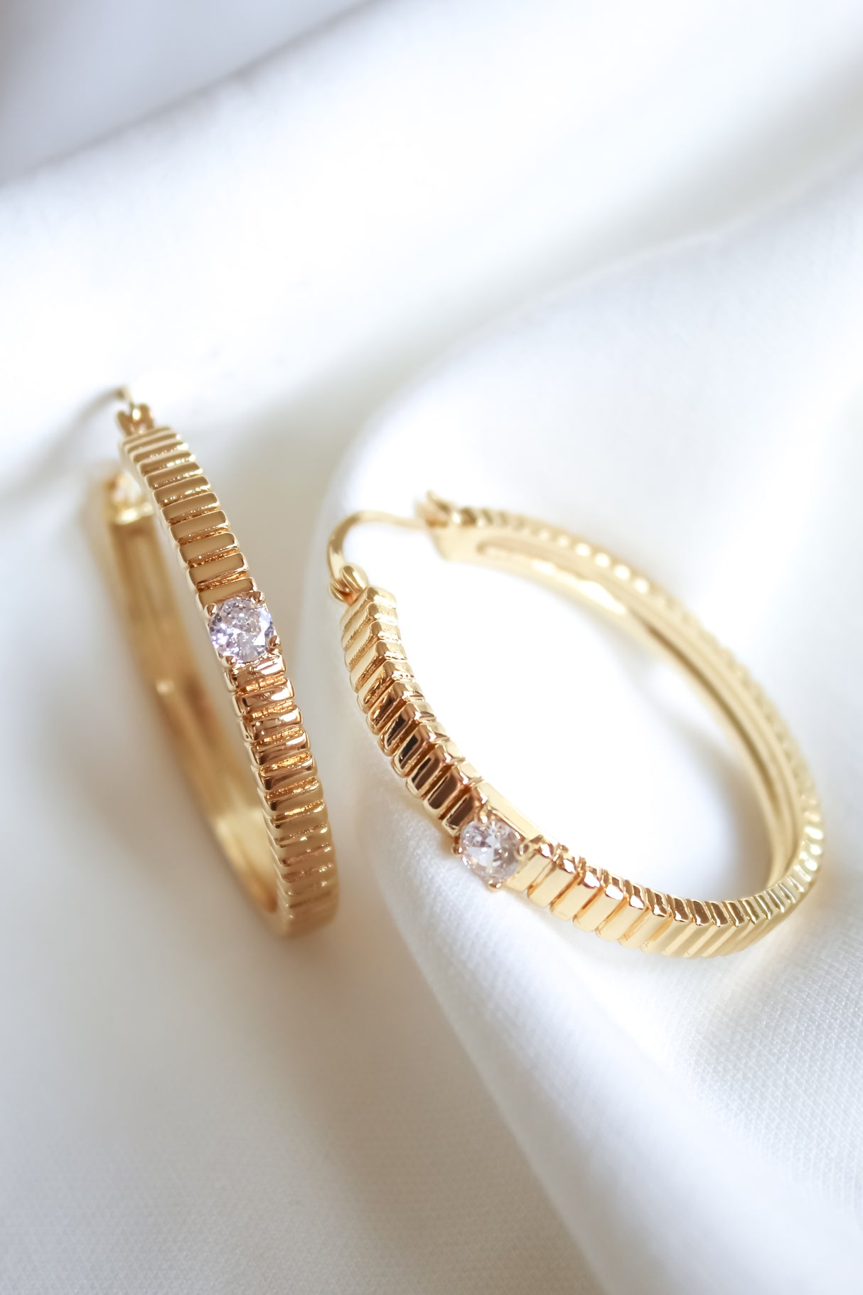 Quinn Hoop Large by Kinsey Designs Archives—gold filled hoops with a textured design and a clear gemstone, displayed on white fabric. Elevate your style with these elegant earrings, now available at our sample sale.