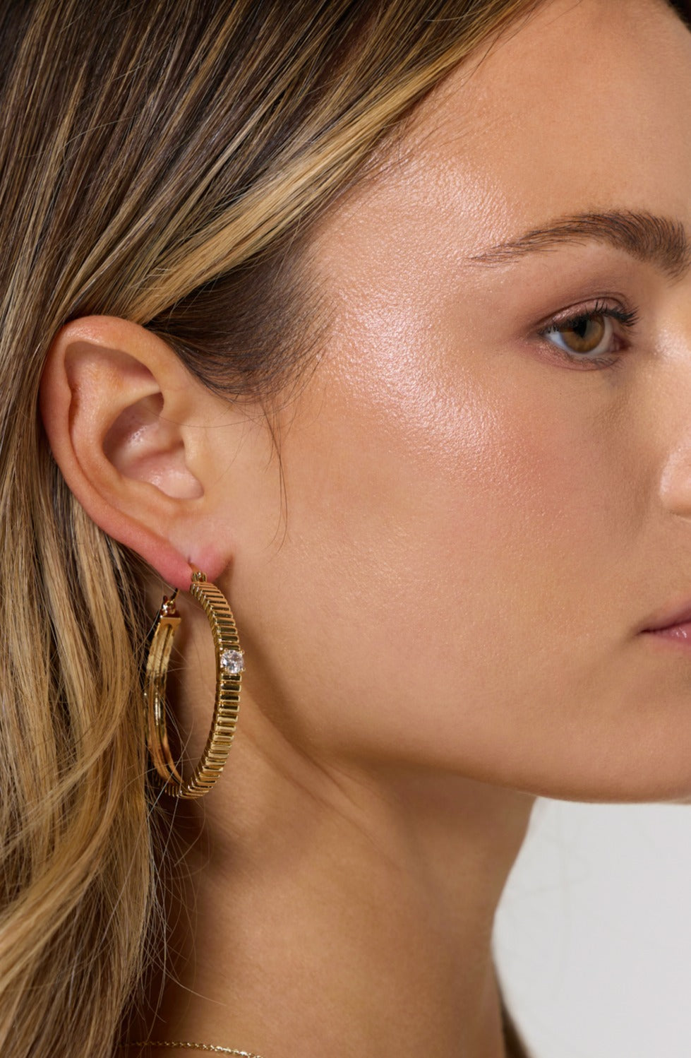 Close-up of a woman with light skin and straight blonde hair wearing Kinsey Designs Archives' Quinn Hoop Large gold-filled earrings.