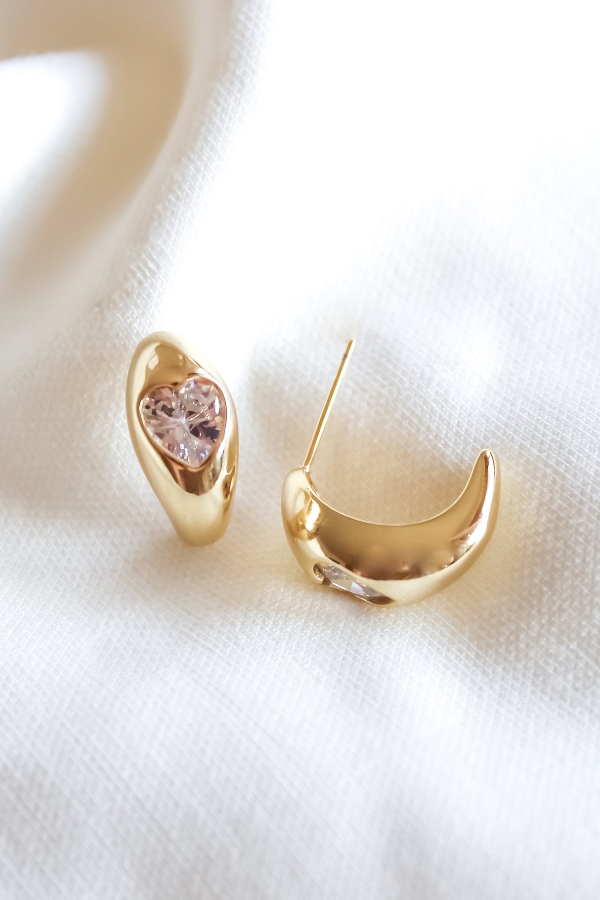 The Robbie Earring by Kinsey Designs Archives features gold-filled, organically curved shapes with a central pink gemstone, displayed on white fabric. Add elegance—shop now at our sample sale!.