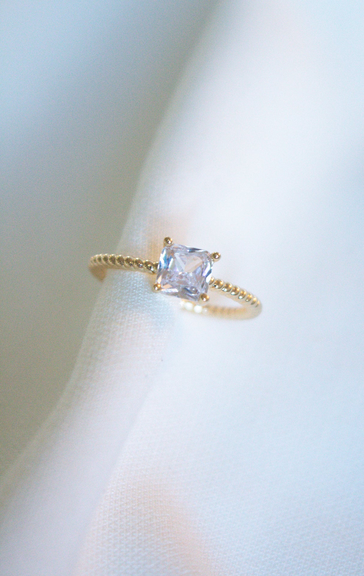 The Rose Ring - Sale by Kinsey Designs Archives features a square-cut cubic zirconia set on a twisted gold filled band, displayed on white fabric.