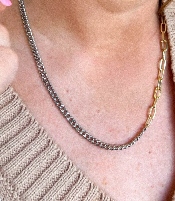A person wearing the Saxon Mixed chain necklace by Kinsey Designs Archives—featuring both gold filled and silver tones—paired with a beige knit sweater.