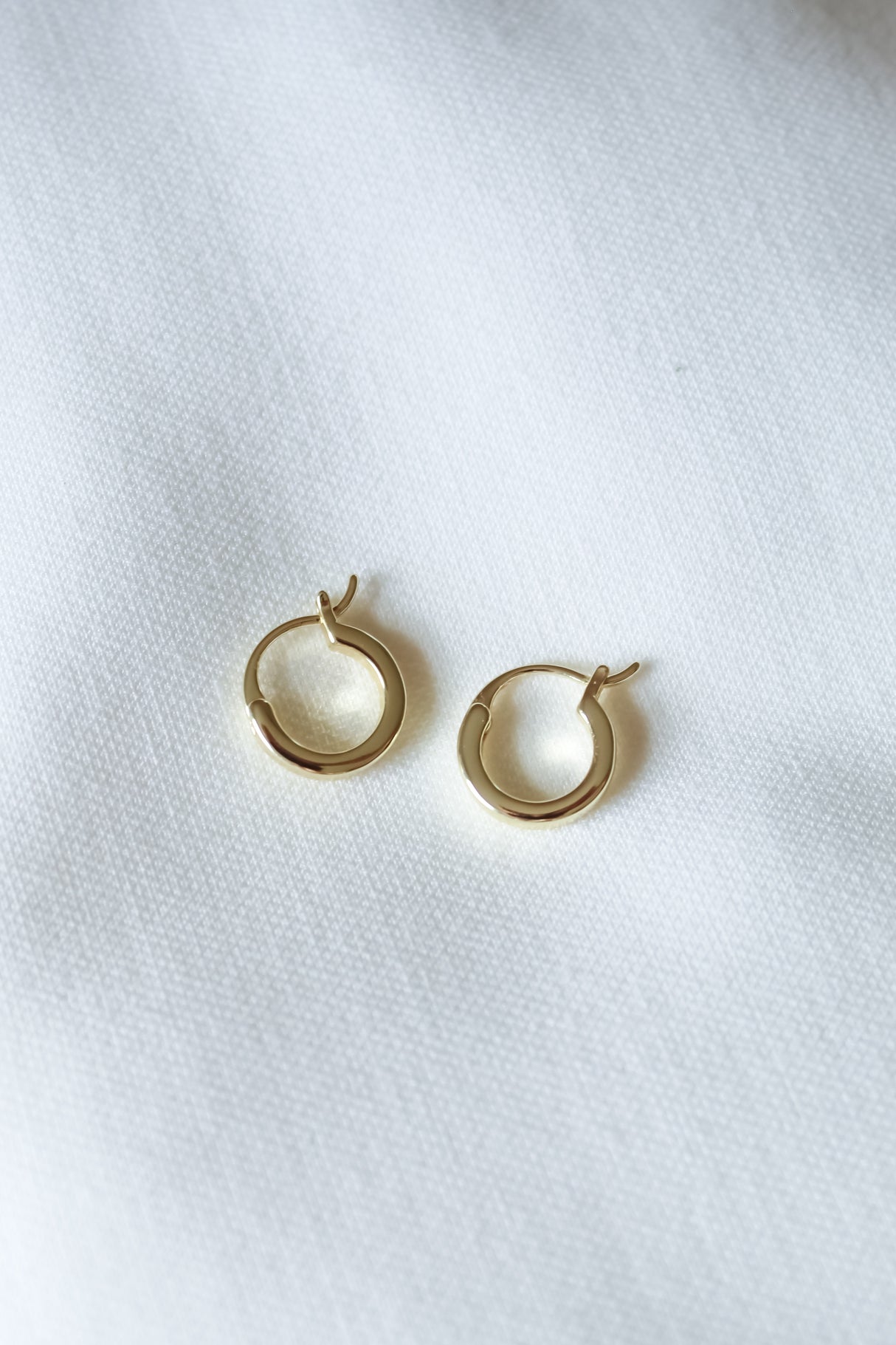 The Kinsey Designs Sleep-In Hoop earrings are small gold-filled hoops with a 0.5" diameter, shown on a white fabric background.