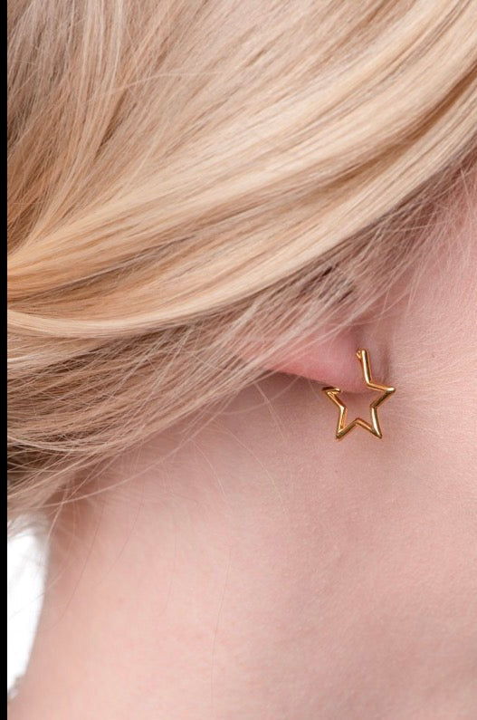 Close-up of an ear wearing the Kinsey Designs Archives Superstar Earring, a gold-filled star-shaped piece (.5" diameter), with light blonde hair in the background.