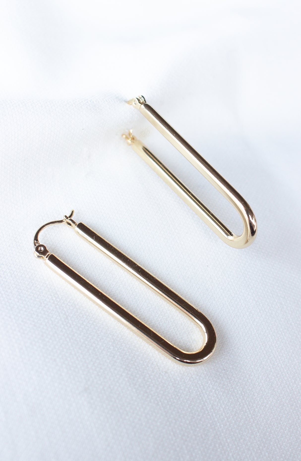 The Kinsey Designs Archives Tate Hoop earrings—a pair of gold filled U-shaped hoops—are shown on a white fabric background. FINAL SALE item.