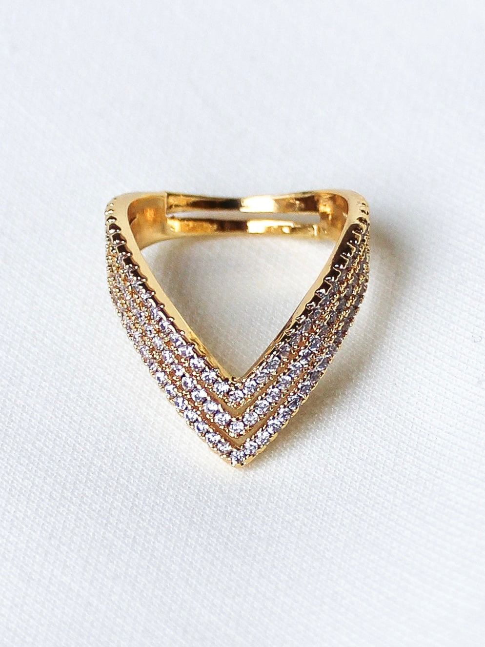 The Veeva Enhancer Ring by Kinsey Designs features a chevron design with three rows of sparkling diamonds, offering minimalist elegance—perfect for everyday wear.